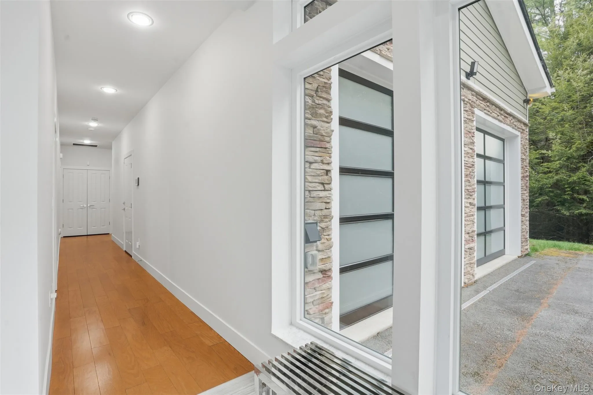 Long hallway with wood-finish flooring and recessed lighting Long hallway with wood-finish flooring and recessed lighting
