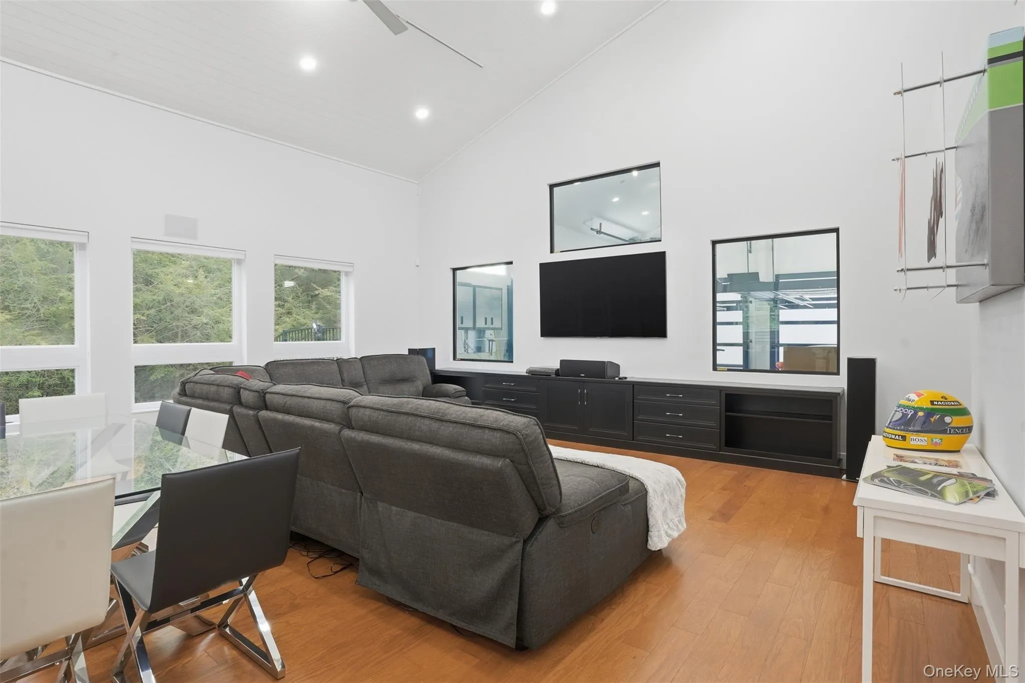 Open-concept living area featuring a vaulted ceiling with recessed lighting, wood-finish flooring, and multiple windows Open-concept living area featuring a vaulted ceiling with recessed lighting, wood-finish flooring, and multiple windows