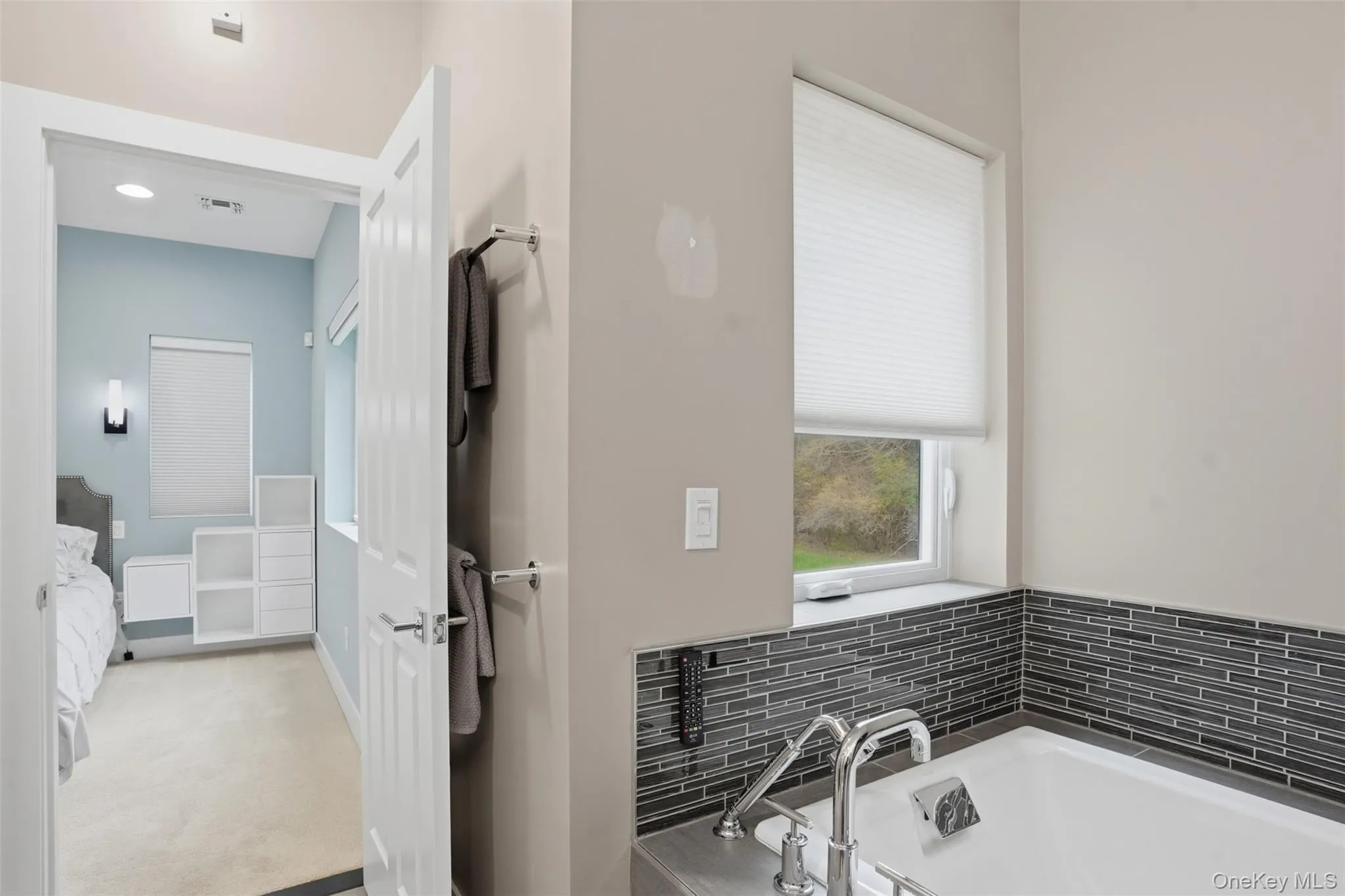 Modern soaking tub with polished chrome fixtures, accented by dark mosaic tile surround Modern soaking tub with polished chrome fixtures, accented by dark mosaic tile surround