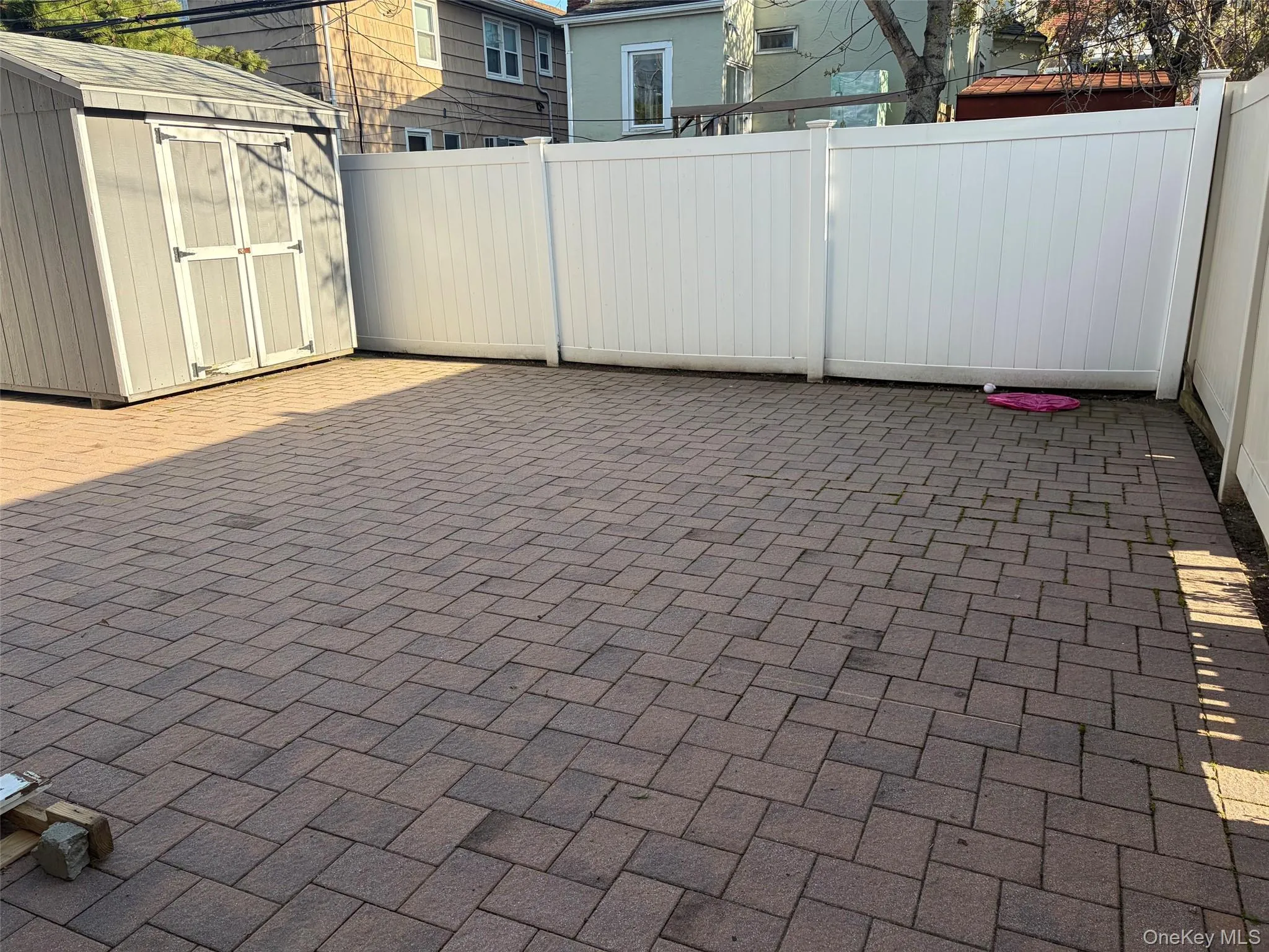 Private backyard with paved patio area featuring herringbone pattern pavers Private backyard with paved patio area featuring herringbone pattern pavers