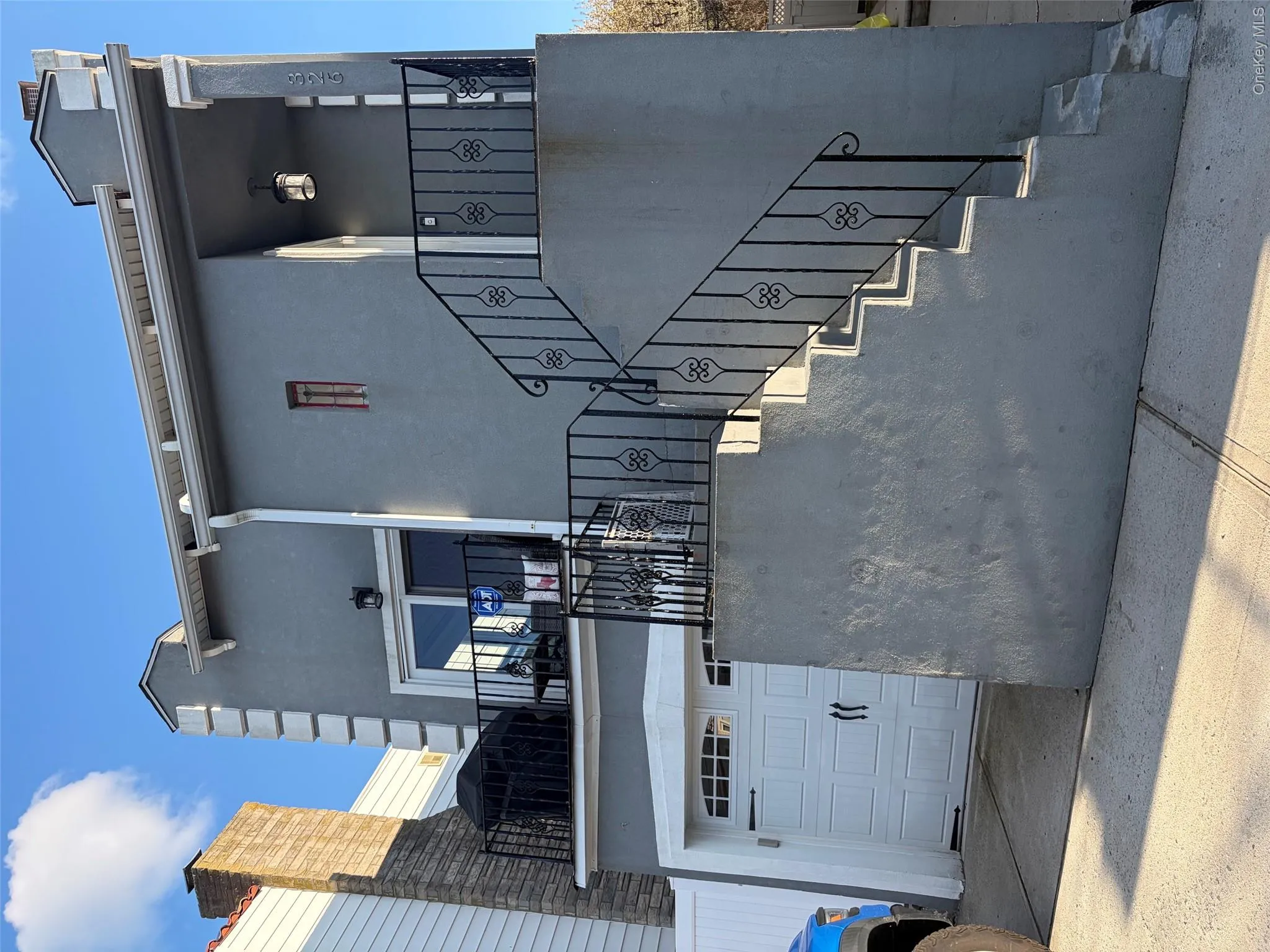 Stucco exterior featuring decorative corner detailing and an upper-level terrace with wrought iron railing Stucco exterior featuring decorative corner detailing and an upper-level terrace with wrought iron railing