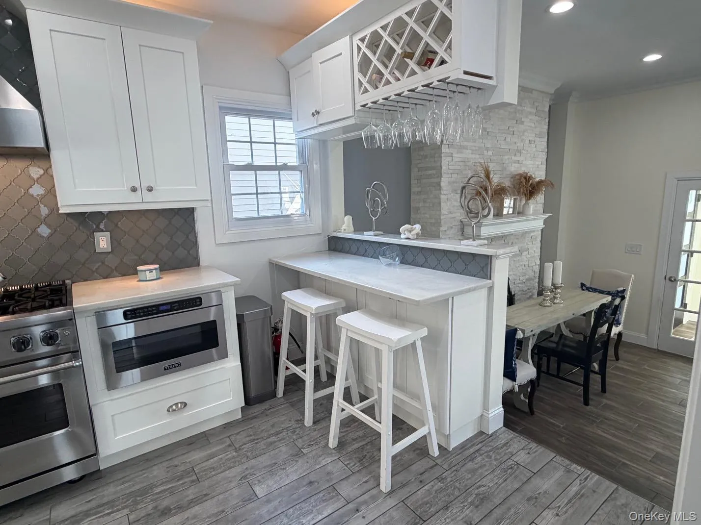 Contemporary kitchen featuring white cabinetry, a built-in wine rack, and stainless steel appliances Contemporary kitchen featuring white cabinetry, a built-in wine rack, and stainless steel appliances