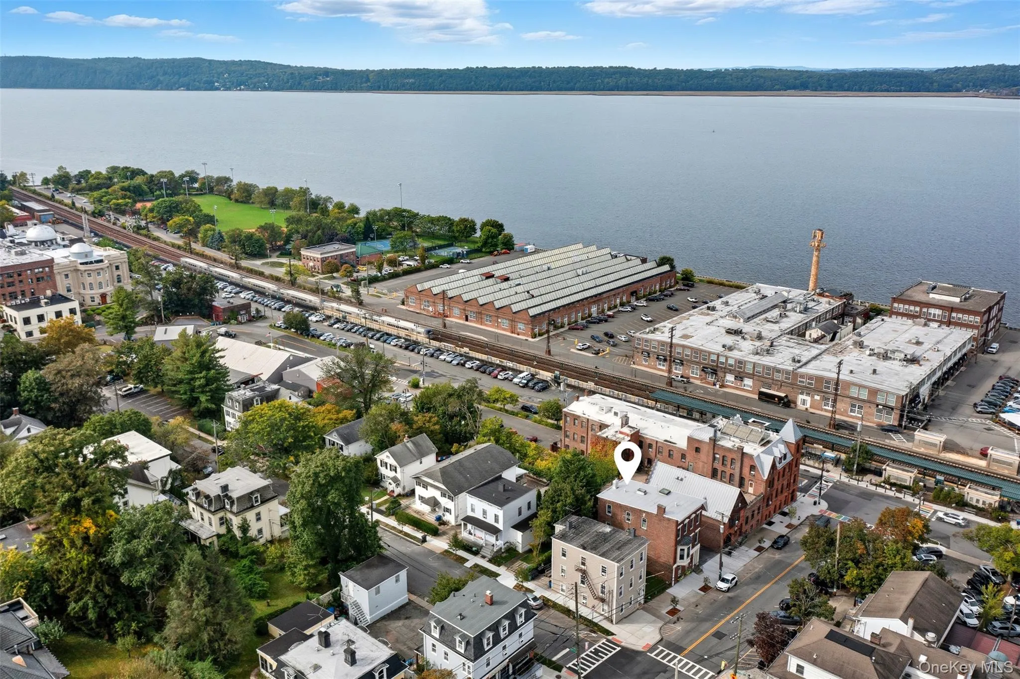 Aerial perspective showcasing a multi-story brick building with a light-colored roof, situated within a developed urban area Aerial perspective showcasing a multi-story brick building with a light-colored roof, situated within a developed urban area