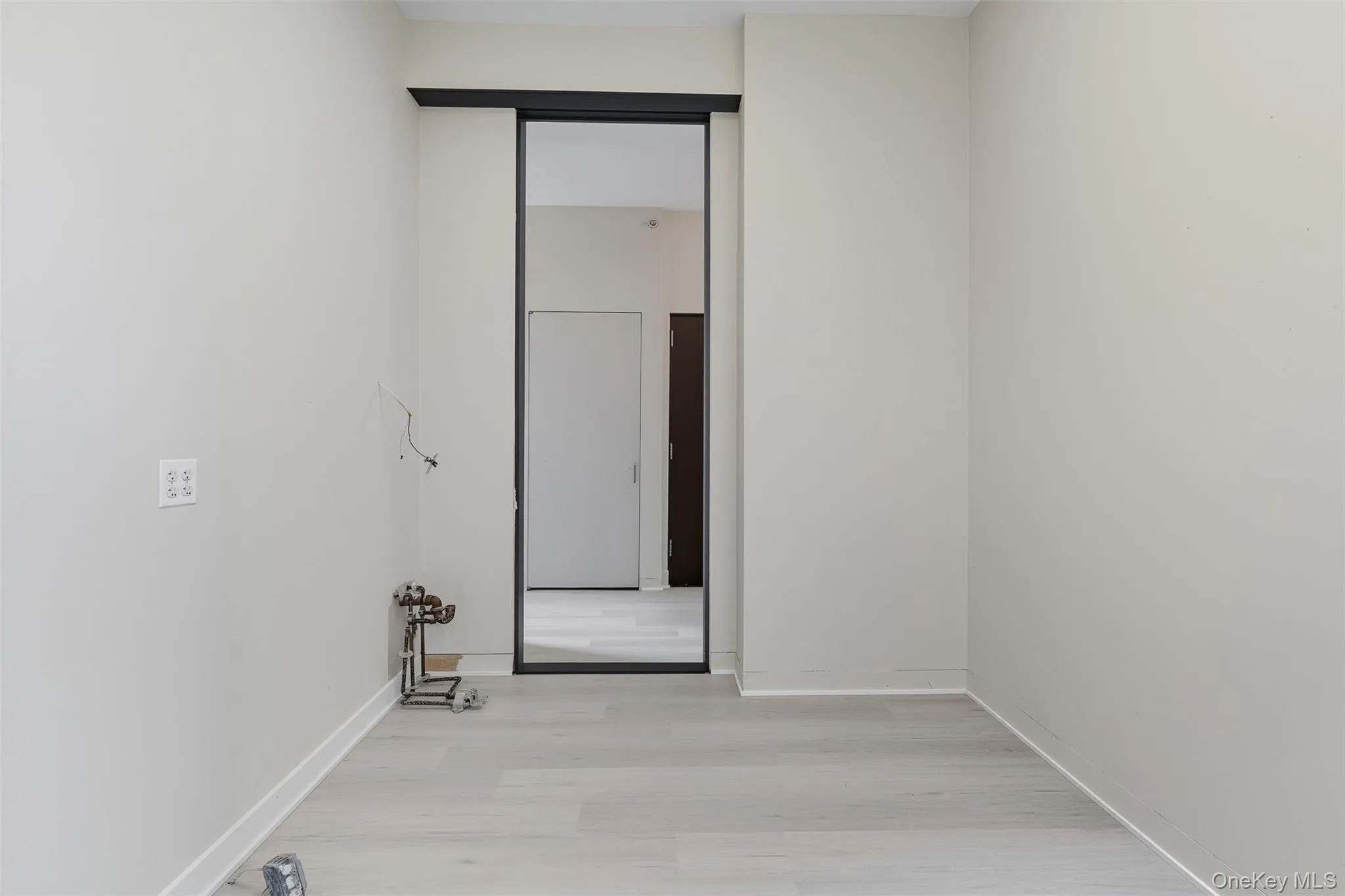 Room featuring light wood-finish flooring, white baseboards, and neutral wall paint Room featuring light wood-finish flooring, white baseboards, and neutral wall paint