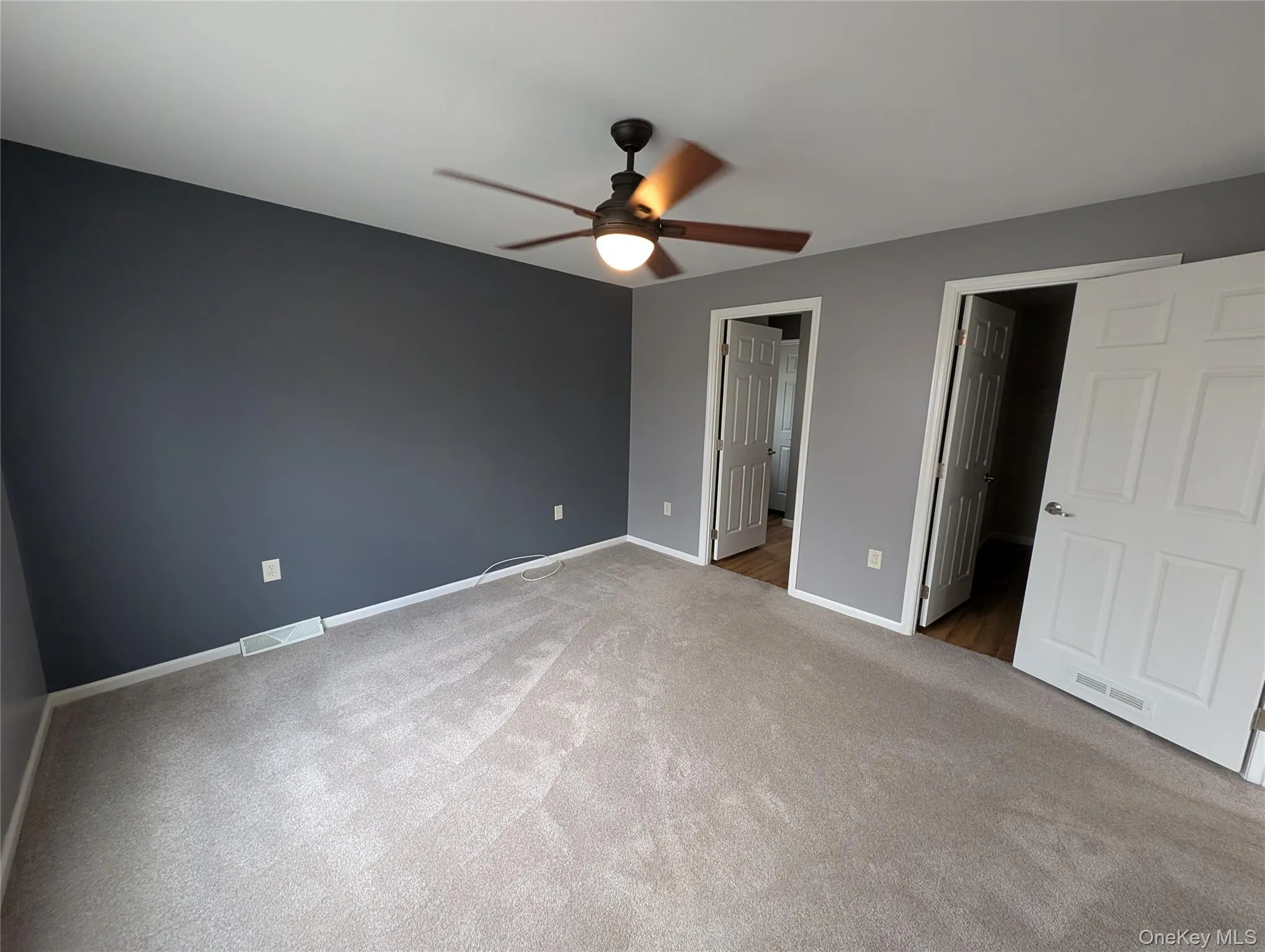 Unfurnished bedroom featuring ensuite bath, ceiling fan, and dark carpet Unfurnished bedroom featuring ensuite bath, ceiling fan, and dark carpet