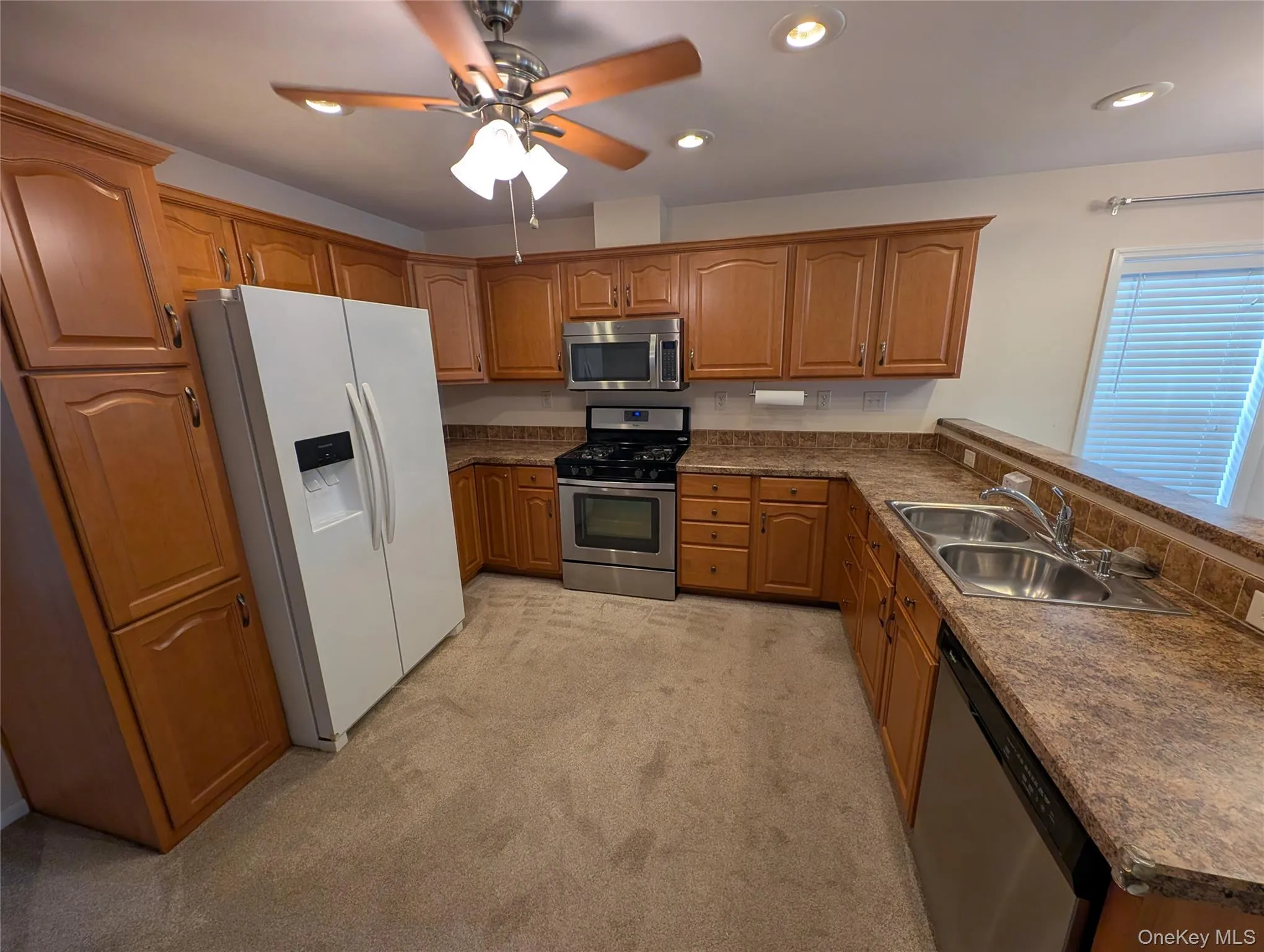 Kitchen with light carpet, stainless steel appliances, ceiling fan, and sink Kitchen with light carpet, stainless steel appliances, ceiling fan, and sink