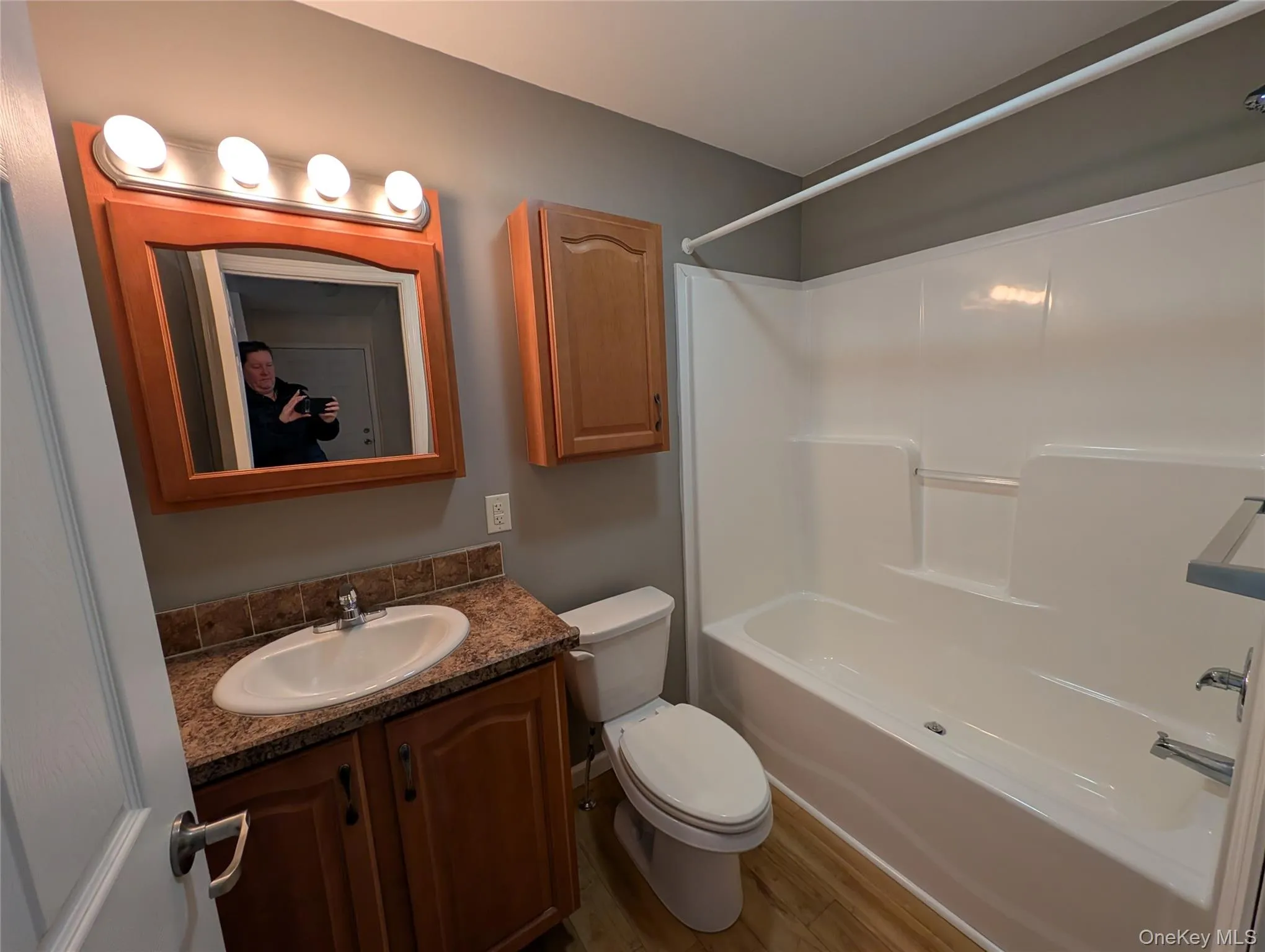 Full bathroom featuring hardwood / wood-style flooring, vanity, toilet, and shower / tub combination Full bathroom featuring hardwood / wood-style flooring, vanity, toilet, and shower / tub combination