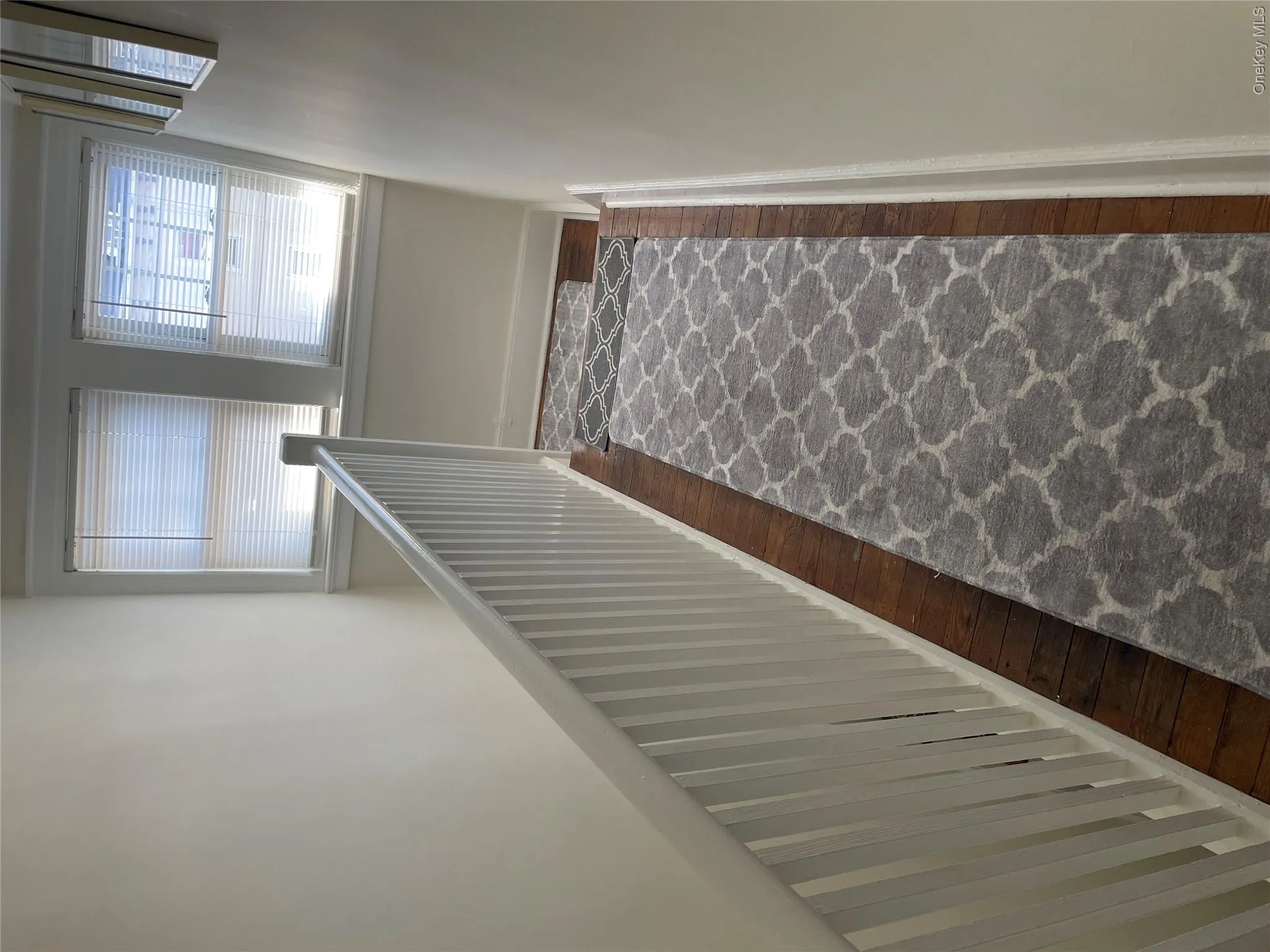 Staircase with wood-finish flooring and a white painted banister Staircase with wood-finish flooring and a white painted banister