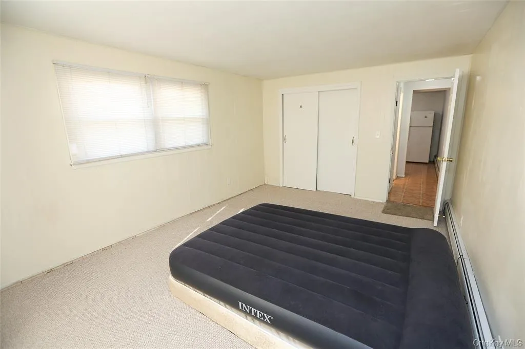 Carpeted room featuring dual windows with blinds, bi-fold closet doors Carpeted room featuring dual windows with blinds, bi-fold closet doors