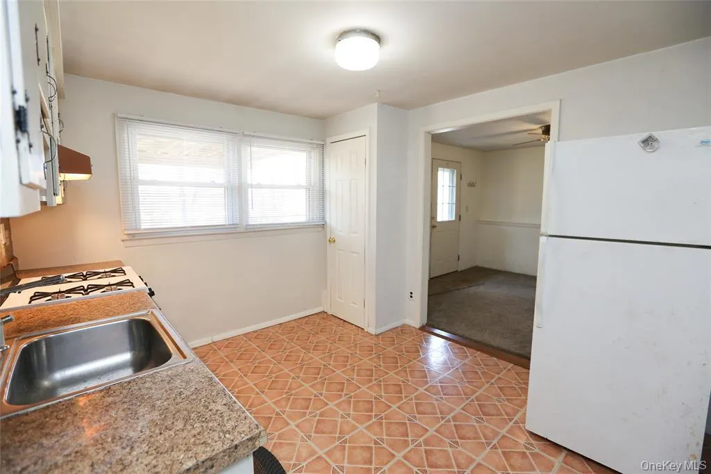 Kitchen featuring patterned tile flooring and a built-in stainless steel sink Kitchen featuring patterned tile flooring and a built-in stainless steel sink