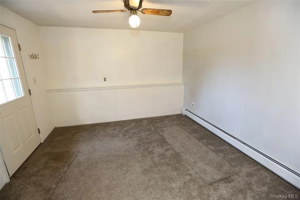 Room featuring a ceiling fan with light fixture, baseboard trim, and a paneled entry door with windowpanes Room featuring a ceiling fan with light fixture, baseboard trim, and a paneled entry door with windowpanes