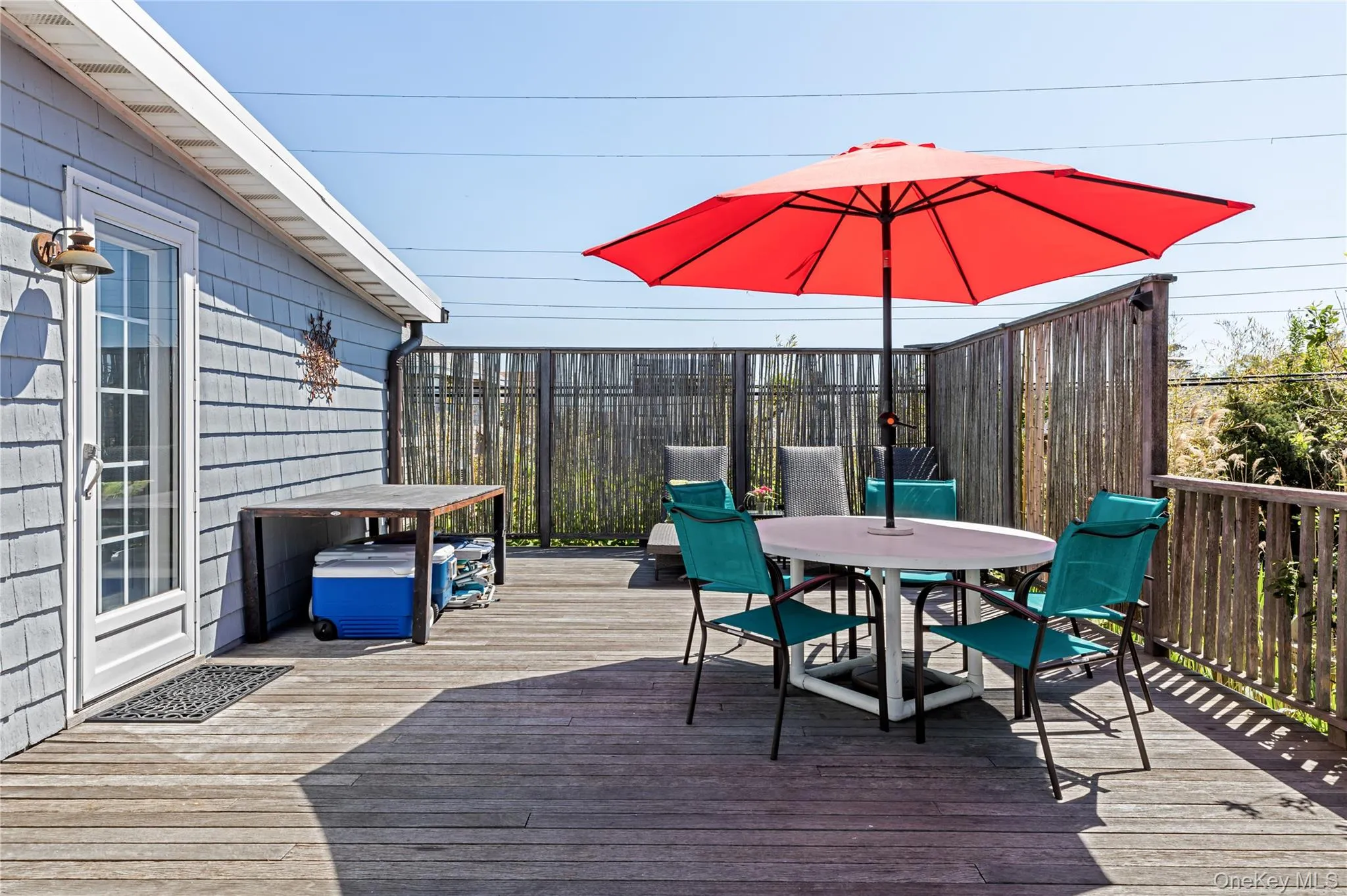 Spacious wood-finish deck with a built-in privacy screen, wood railing, and shingle siding exterior Spacious wood-finish deck with a built-in privacy screen, wood railing, and shingle siding exterior