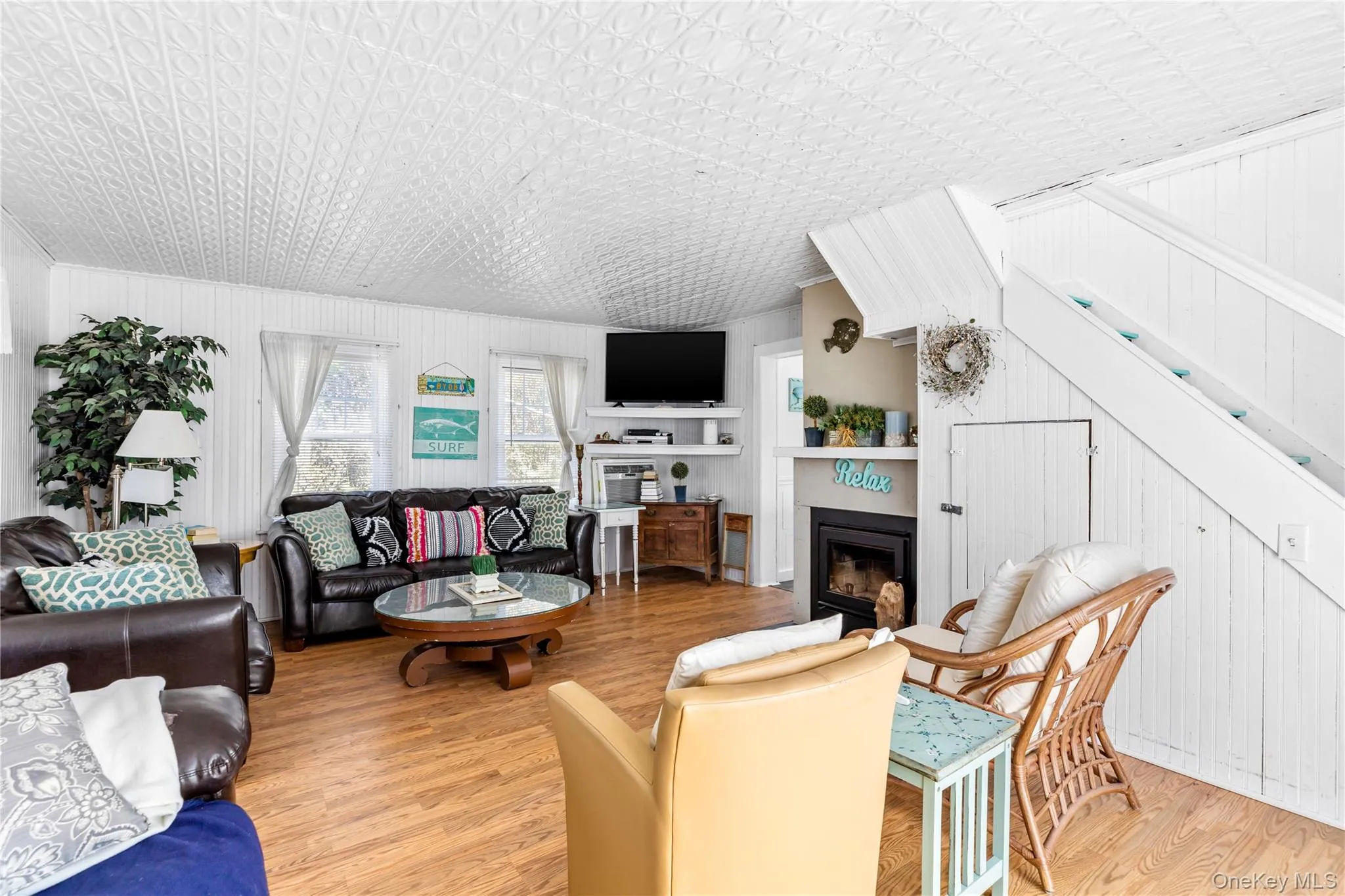Open concept living space featuring wood-finish flooring, white paneled walls, and a decorative ceiling Open concept living space featuring wood-finish flooring, white paneled walls, and a decorative ceiling