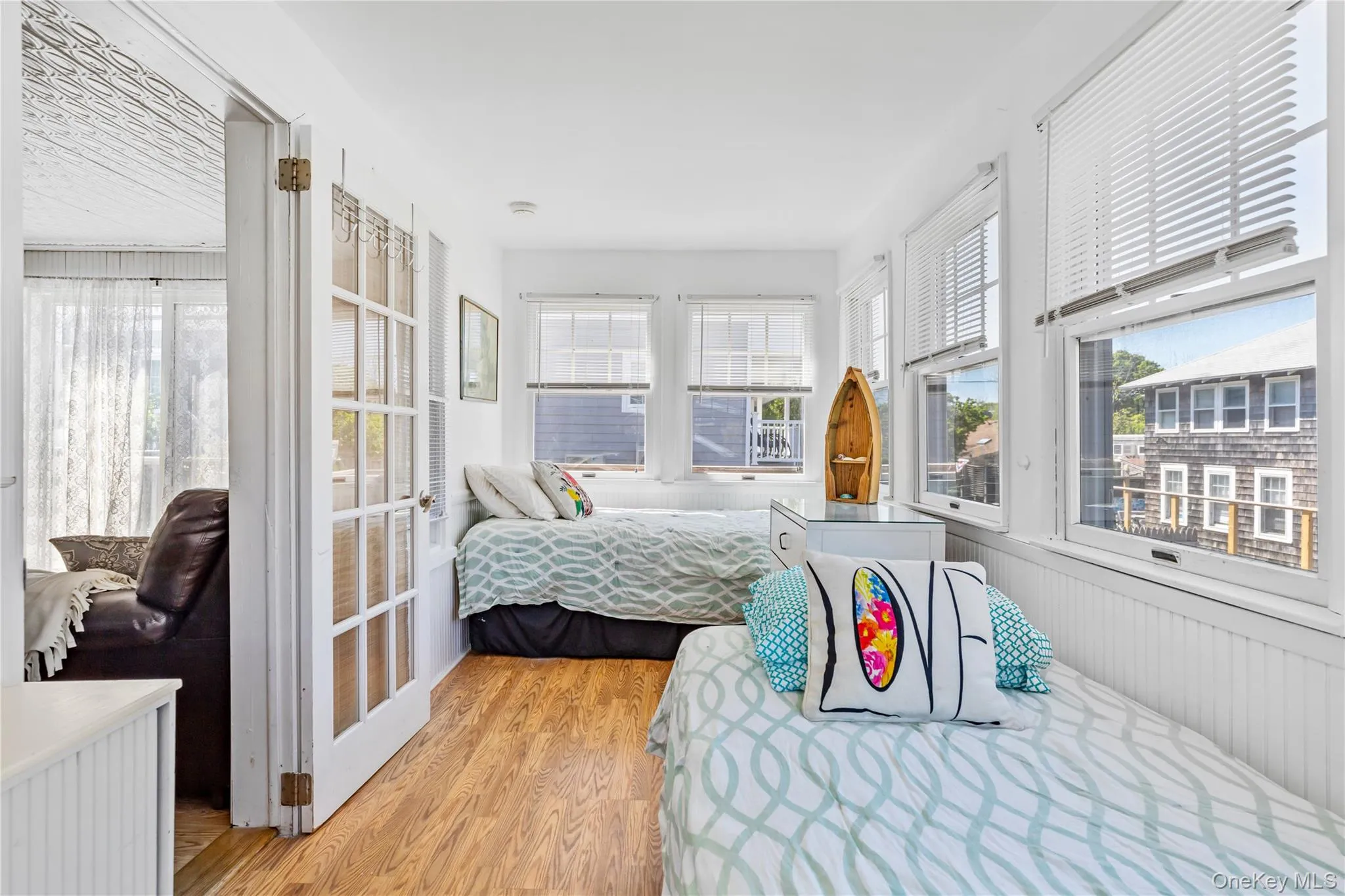 Bright interior space featuring wood-finish flooring and white vertical paneling Bright interior space featuring wood-finish flooring and white vertical paneling