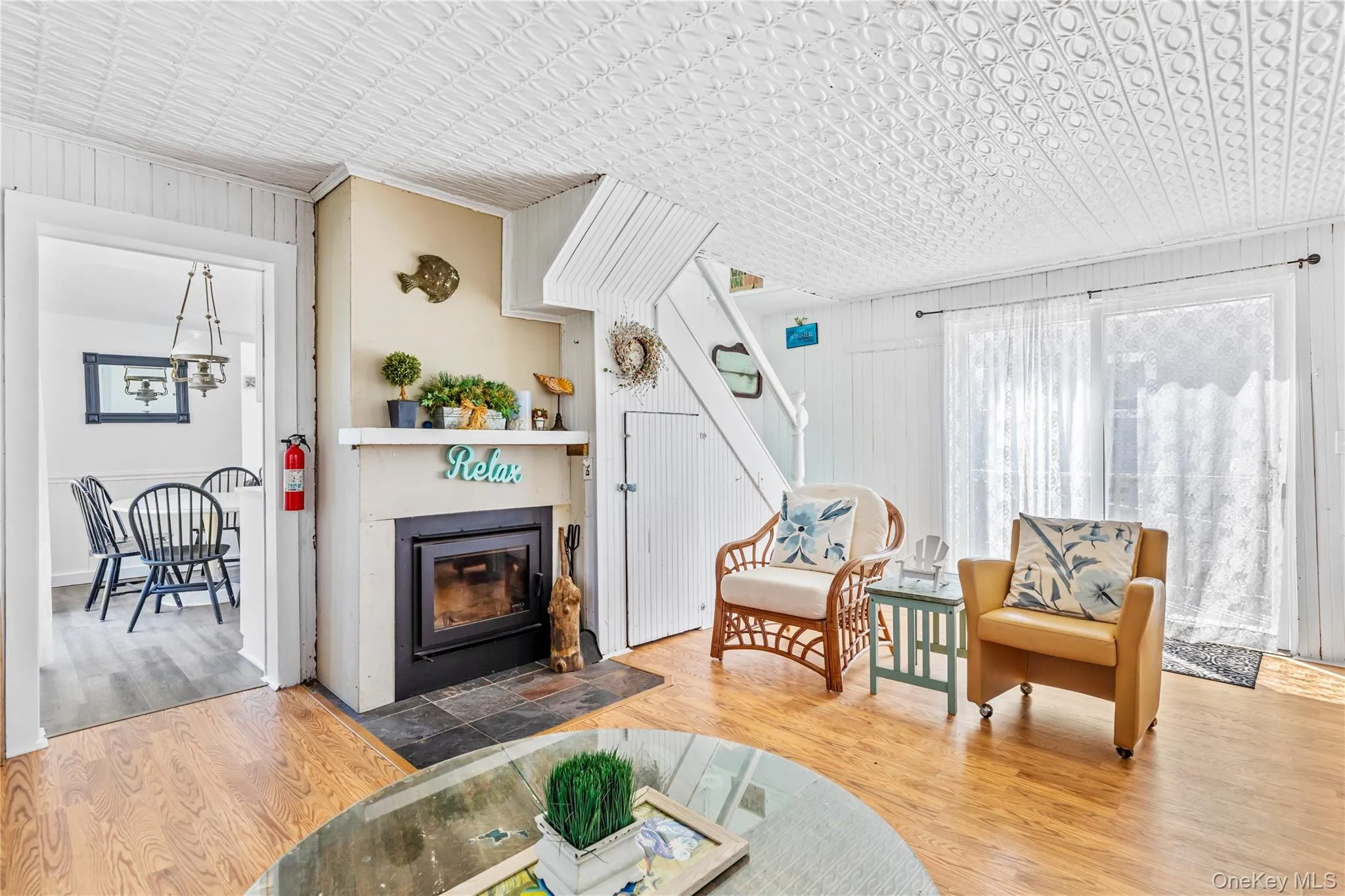 Living area featuring wood-finish flooring, a wood-burning fireplace with a slate hearth, and a white beadboard wall finish Living area featuring wood-finish flooring, a wood-burning fireplace with a slate hearth, and a white beadboard wall finish