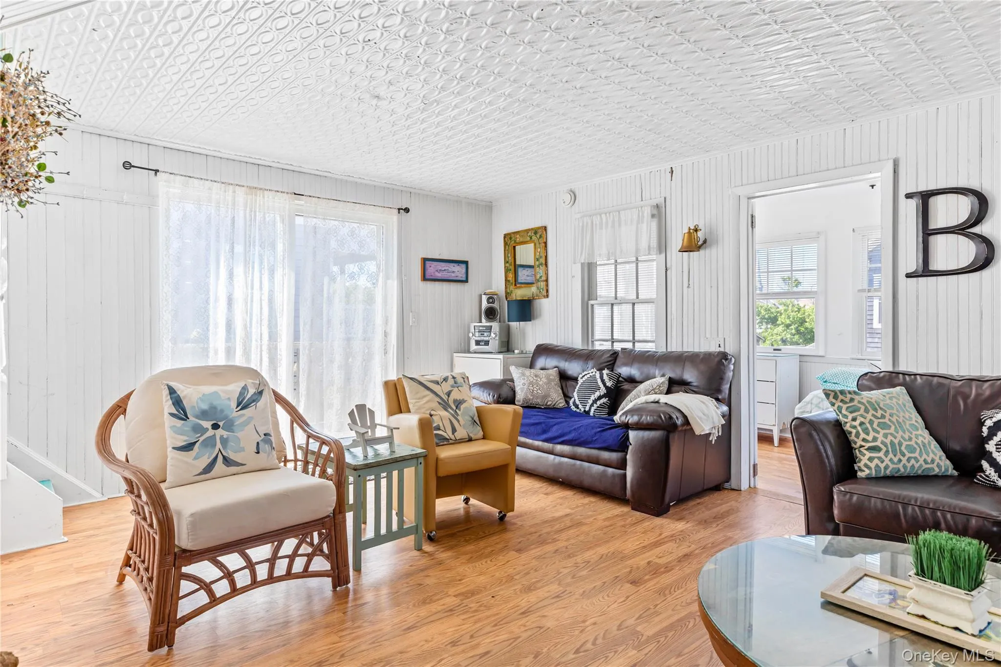 Living area featuring wood-finish flooring, white shiplap walls, and a white pressed-tin ceiling Living area featuring wood-finish flooring, white shiplap walls, and a white pressed-tin ceiling