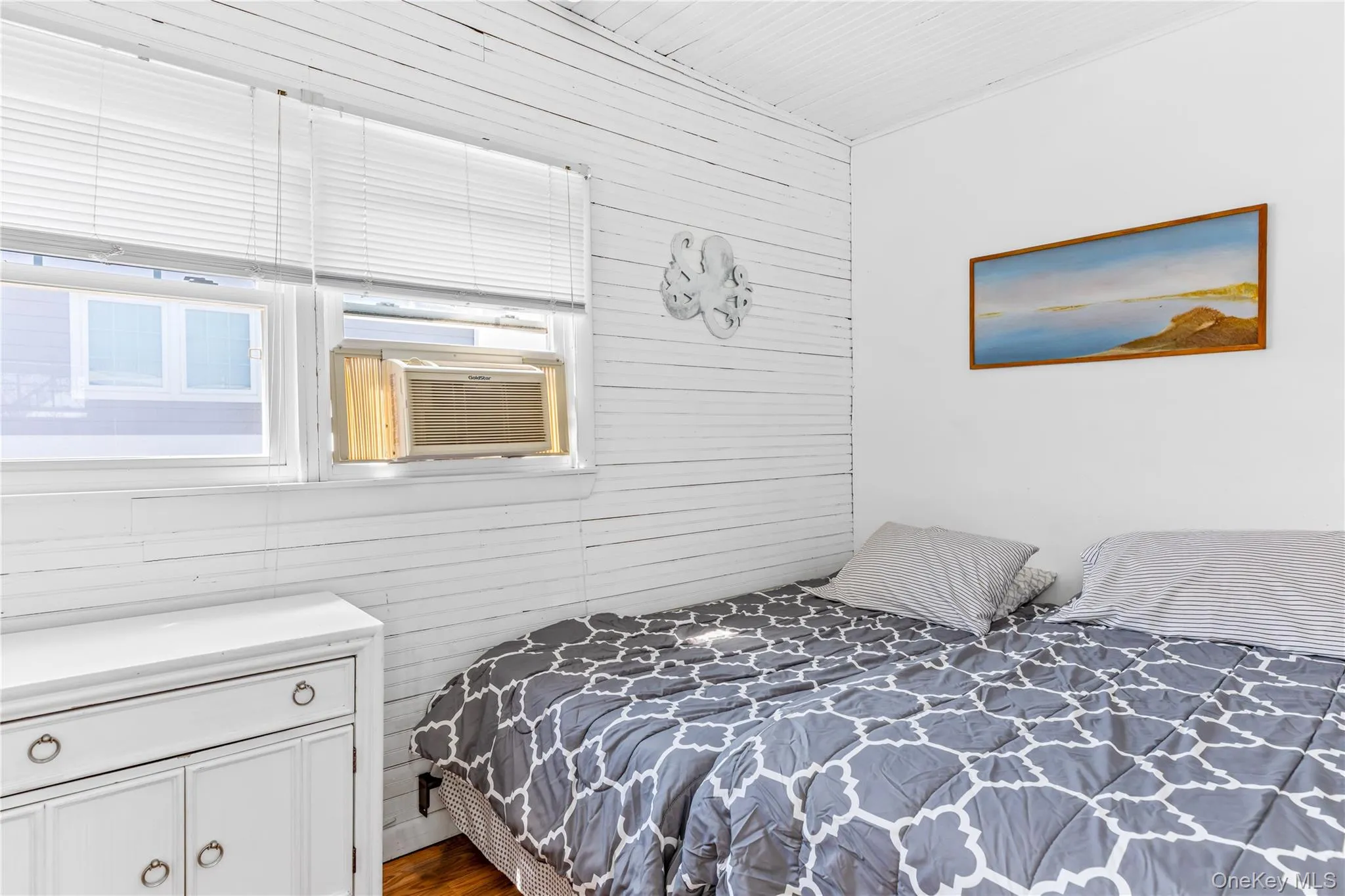 Room featuring white shiplap walls, smooth white ceiling, and a window air conditioning unit Room featuring white shiplap walls, smooth white ceiling, and a window air conditioning unit
