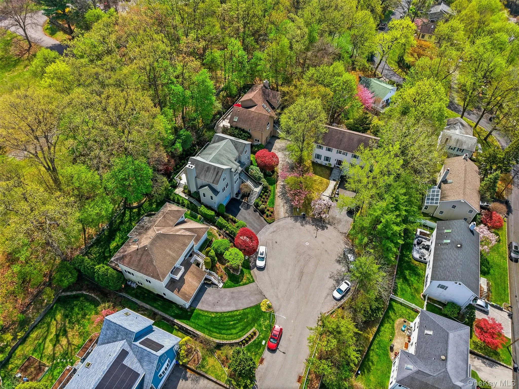 Residential property featuring mature tree coverage, a cul-de-sac street, and paved driveways Residential property featuring mature tree coverage, a cul-de-sac street, and paved driveways