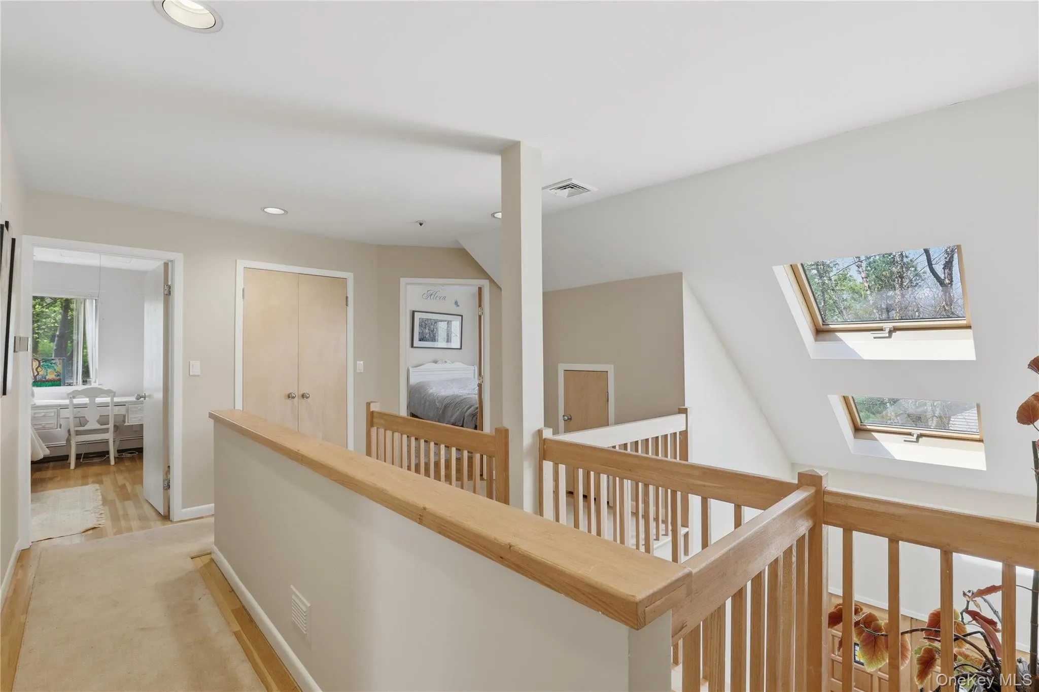 Upper-level landing featuring natural wood railings and multiple skylights Upper-level landing featuring natural wood railings and multiple skylights