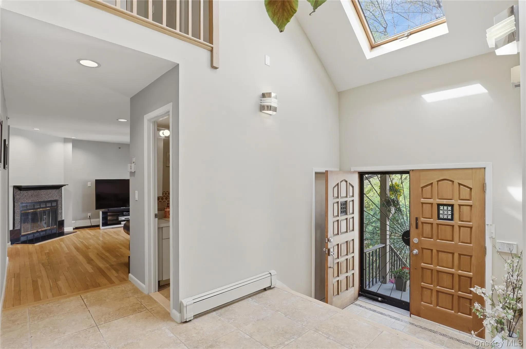 Vaulted foyer entry featuring two wood-panel doors, a skylight, and travertine-style floor tiles Vaulted foyer entry featuring two wood-panel doors, a skylight, and travertine-style floor tiles
