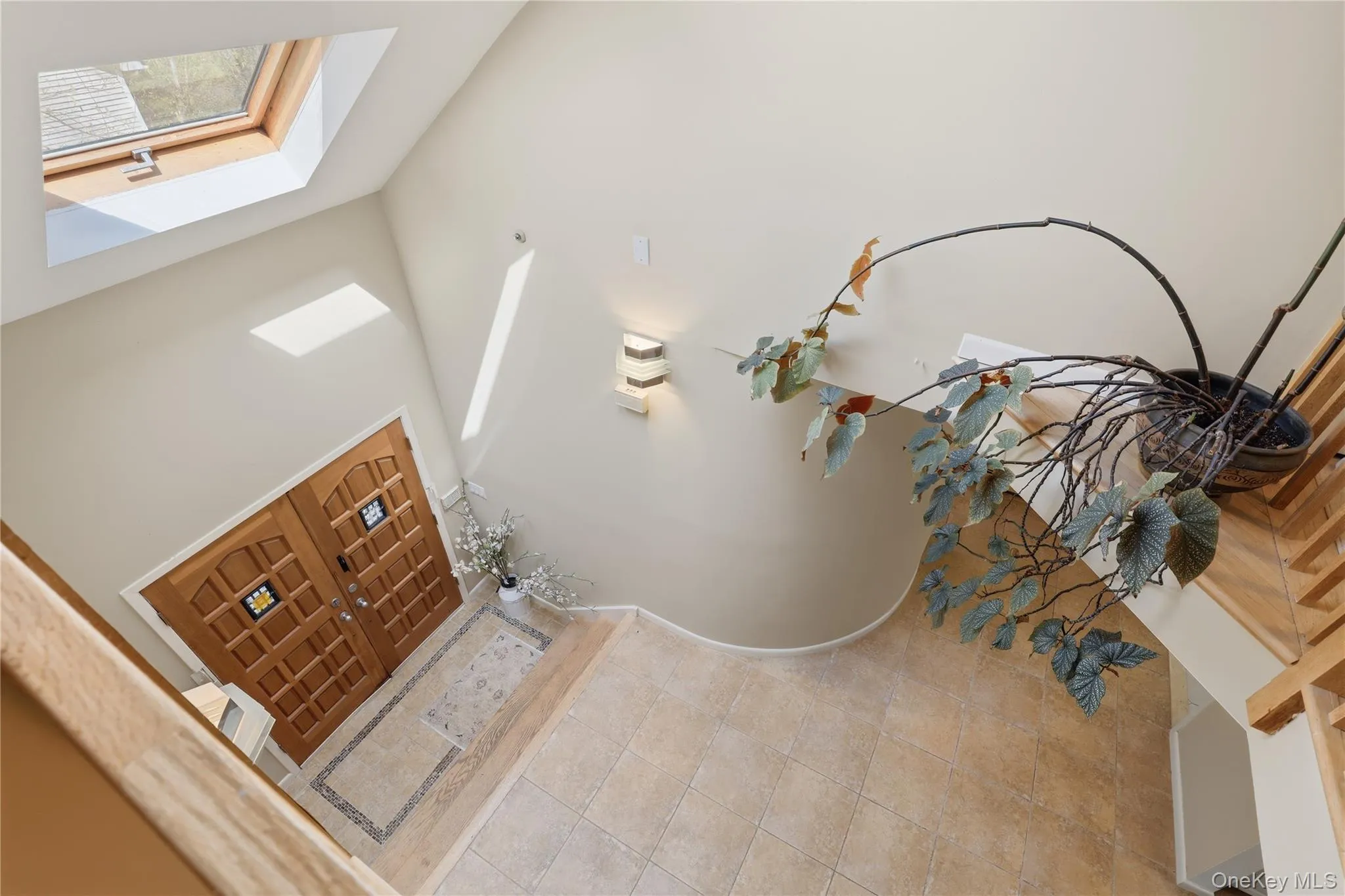 Grand entry featuring a skylight, double wood-panel doors with decorative inserts, and ceramic tile flooring with a mosaic border Grand entry featuring a skylight, double wood-panel doors with decorative inserts, and ceramic tile flooring with a mosaic border