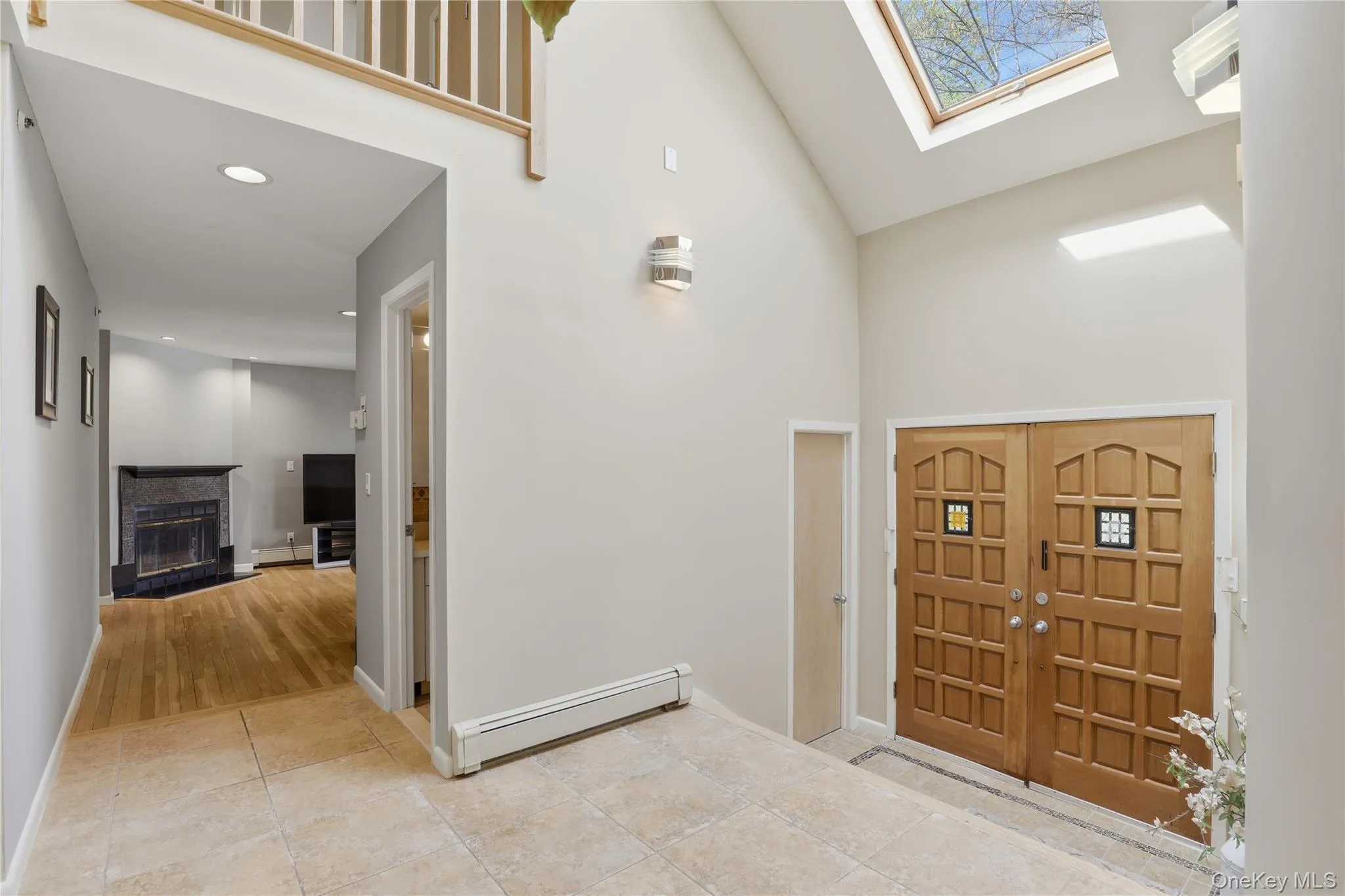 Vaulted entry with skylight, dual wood entry doors with decorative inserts, and light-toned tile flooring Vaulted entry with skylight, dual wood entry doors with decorative inserts, and light-toned tile flooring