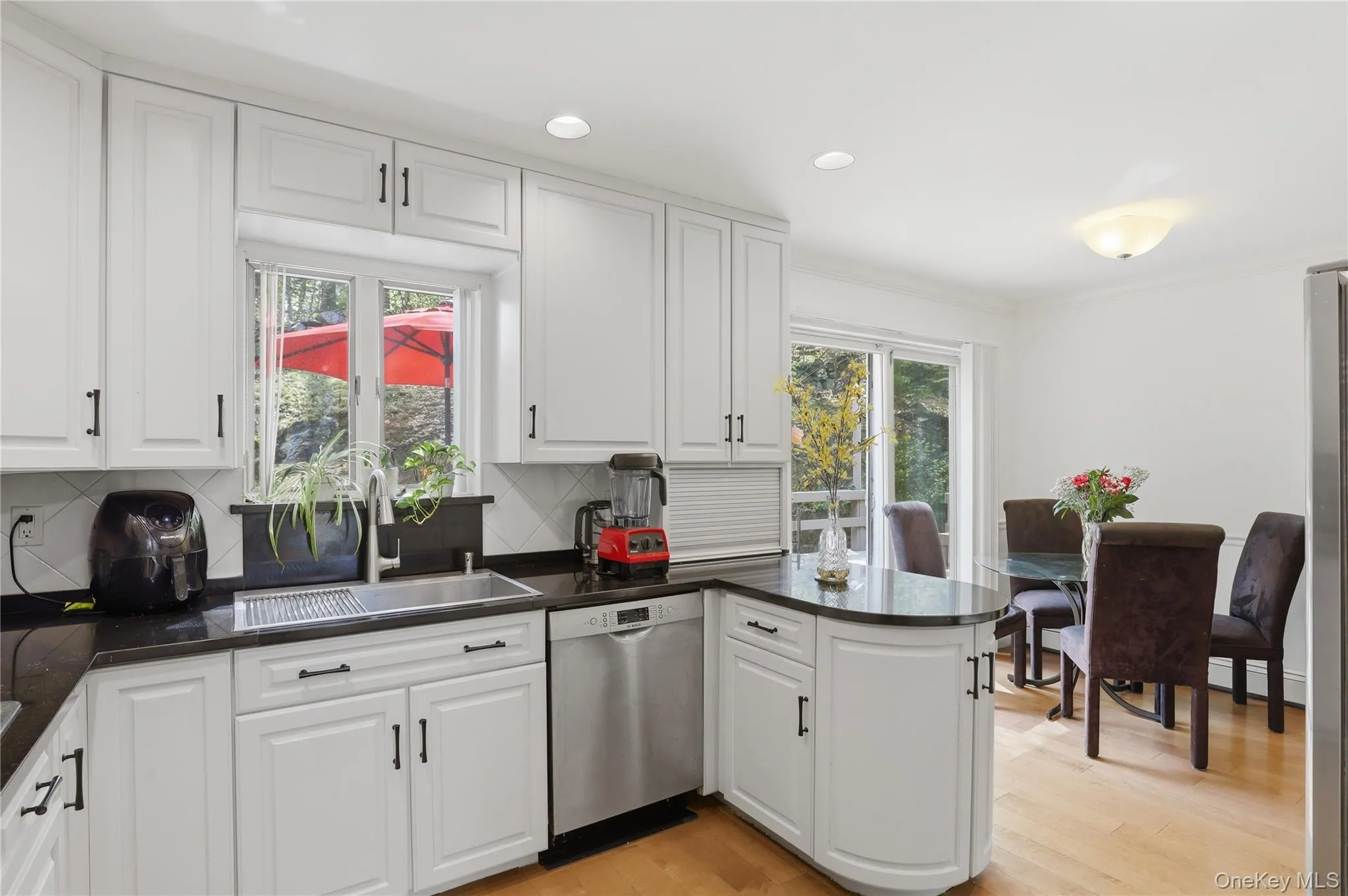 White kitchen cabinetry with black hardware, dark countertops, and a stainless steel sink White kitchen cabinetry with black hardware, dark countertops, and a stainless steel sink
