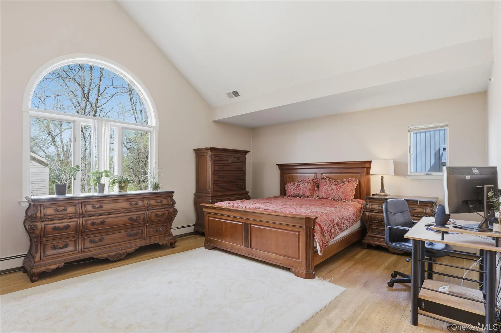 Spacious primary bedroom featuring vaulted ceilings, wood-finish flooring, and light-toned walls Spacious primary bedroom featuring vaulted ceilings, wood-finish flooring, and light-toned walls