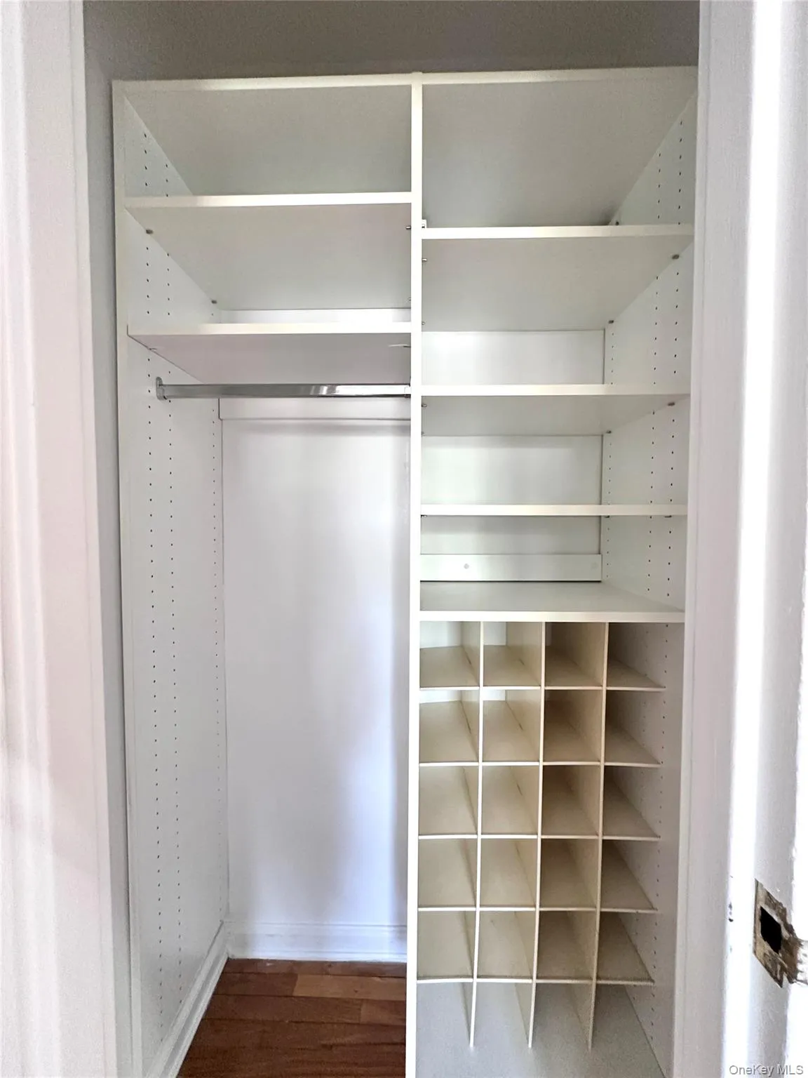 Custom closet system featuring white shelving, integrated hanging rod, and dedicated shoe storage compartments Custom closet system featuring white shelving, integrated hanging rod, and dedicated shoe storage compartments
