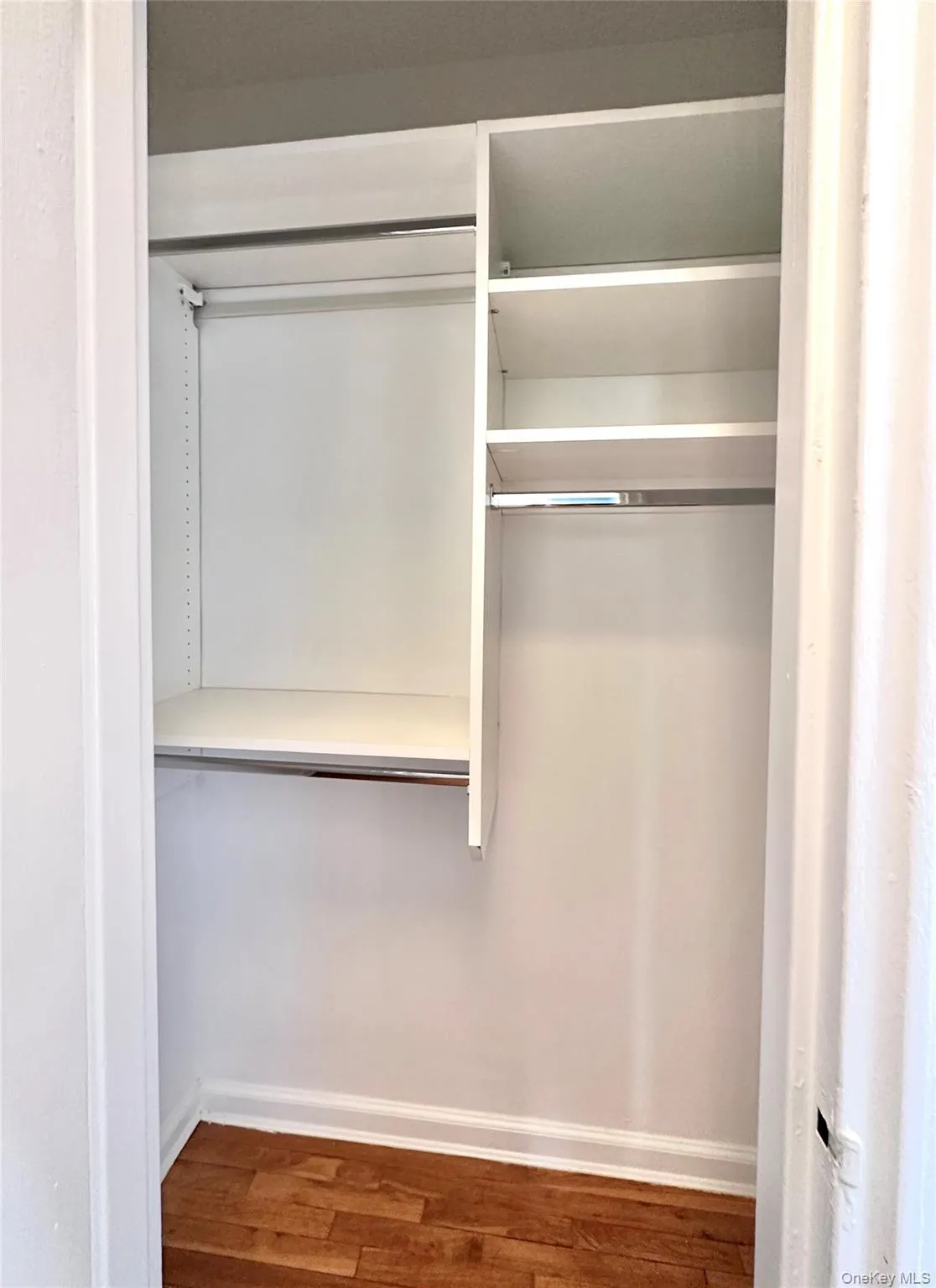 Built-in closet system featuring white shelving and hanging rods Built-in closet system featuring white shelving and hanging rods