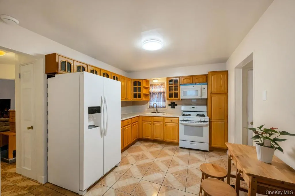 Kitchen featuring wood-finish cabinetry, white countertops, and patterned floor tiling Kitchen featuring wood-finish cabinetry, white countertops, and patterned floor tiling