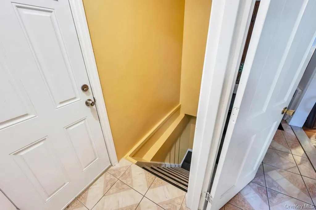 Entryway featuring tiled flooring, a paneled white door, and a staircase with dark treads and white risers Entryway featuring tiled flooring, a paneled white door, and a staircase with dark treads and white risers