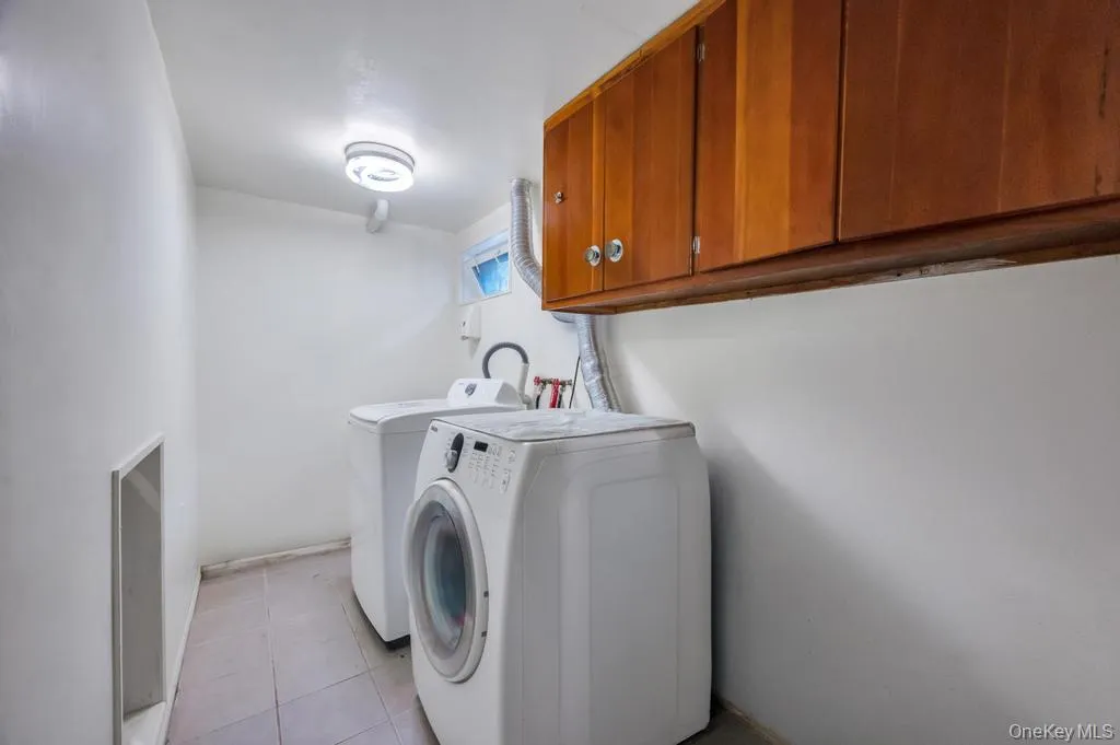 Dedicated utility space featuring overhead wood cabinetry, durable tile flooring, and integrated ceiling lighting Dedicated utility space featuring overhead wood cabinetry, durable tile flooring, and integrated ceiling lighting