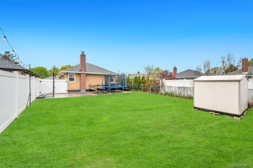 Expansive green lawn framed by a white privacy fence Expansive green lawn framed by a white privacy fence