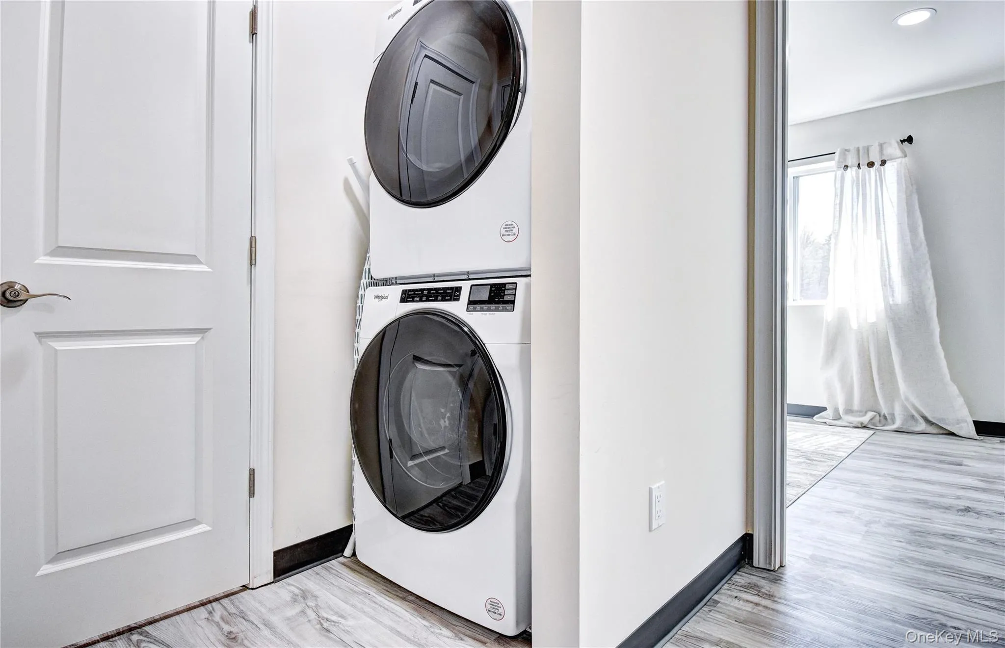 Laundry room with stacked washer / dryer and light hardwood / wood-style floors Laundry room with stacked washer / dryer and light hardwood / wood-style floors