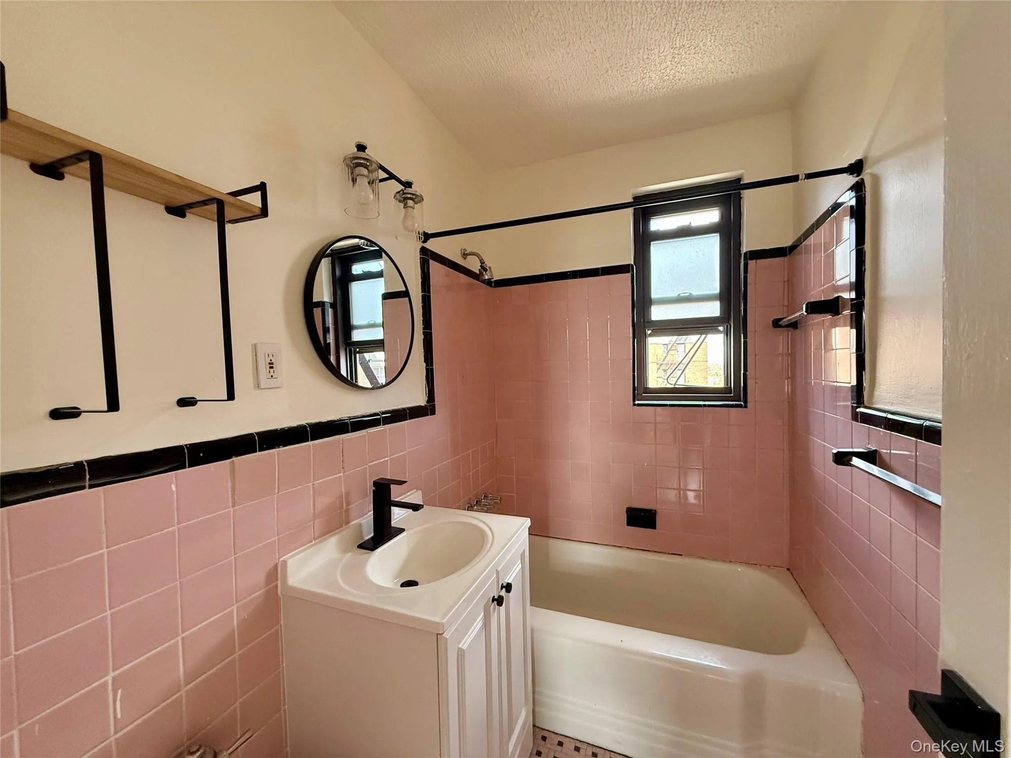 Original bathroom with updated sink, lights and mirror. Window for ventilation, tile on the floors and walls. Original bathroom with updated sink, lights and mirror. Window for ventilation, tile on the floors and walls.