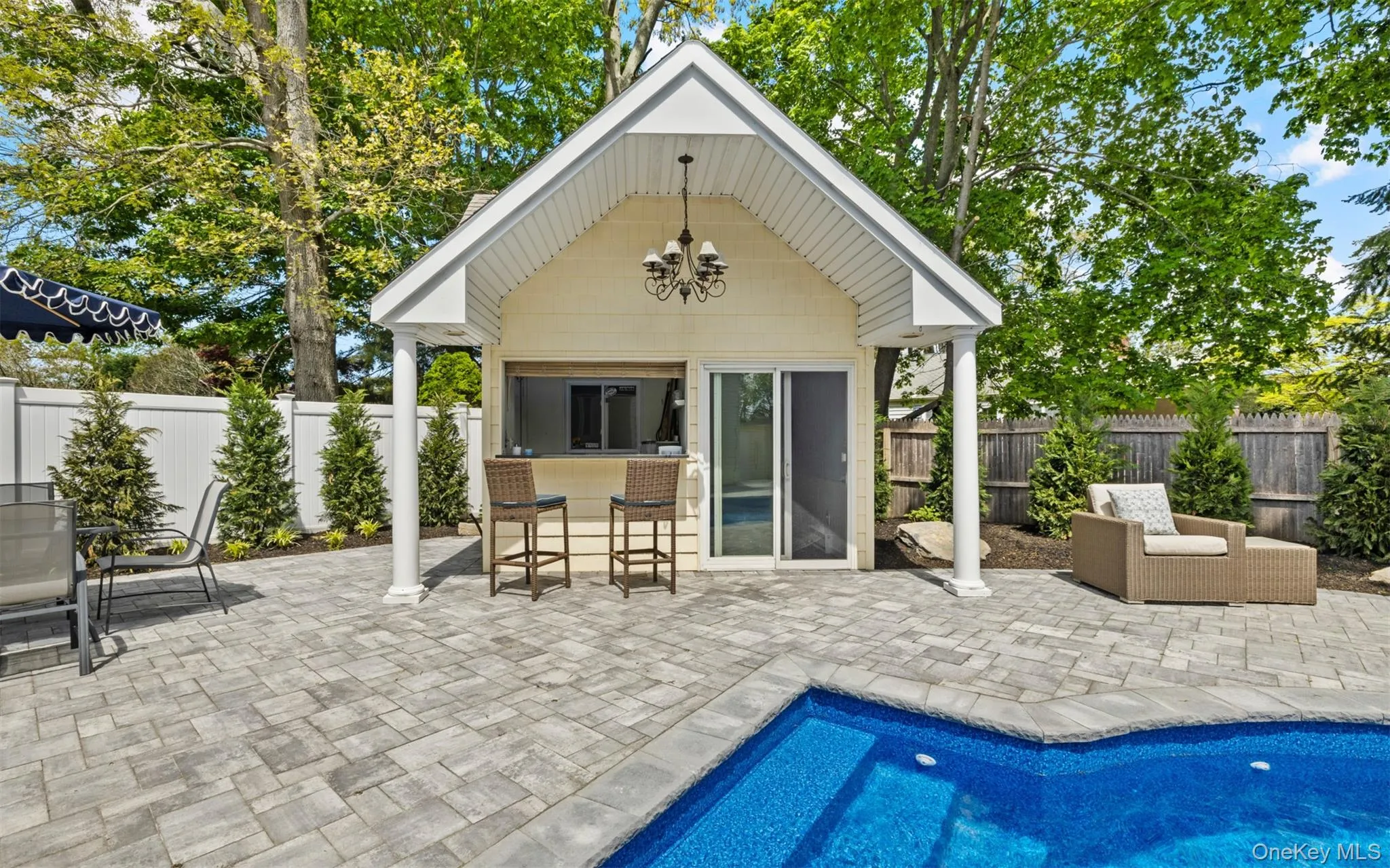 Dedicated pool house featuring an outdoor bar area, covered porch, glass sliding door, and chandelier lighting Dedicated pool house featuring an outdoor bar area, covered porch, glass sliding door, and chandelier lighting