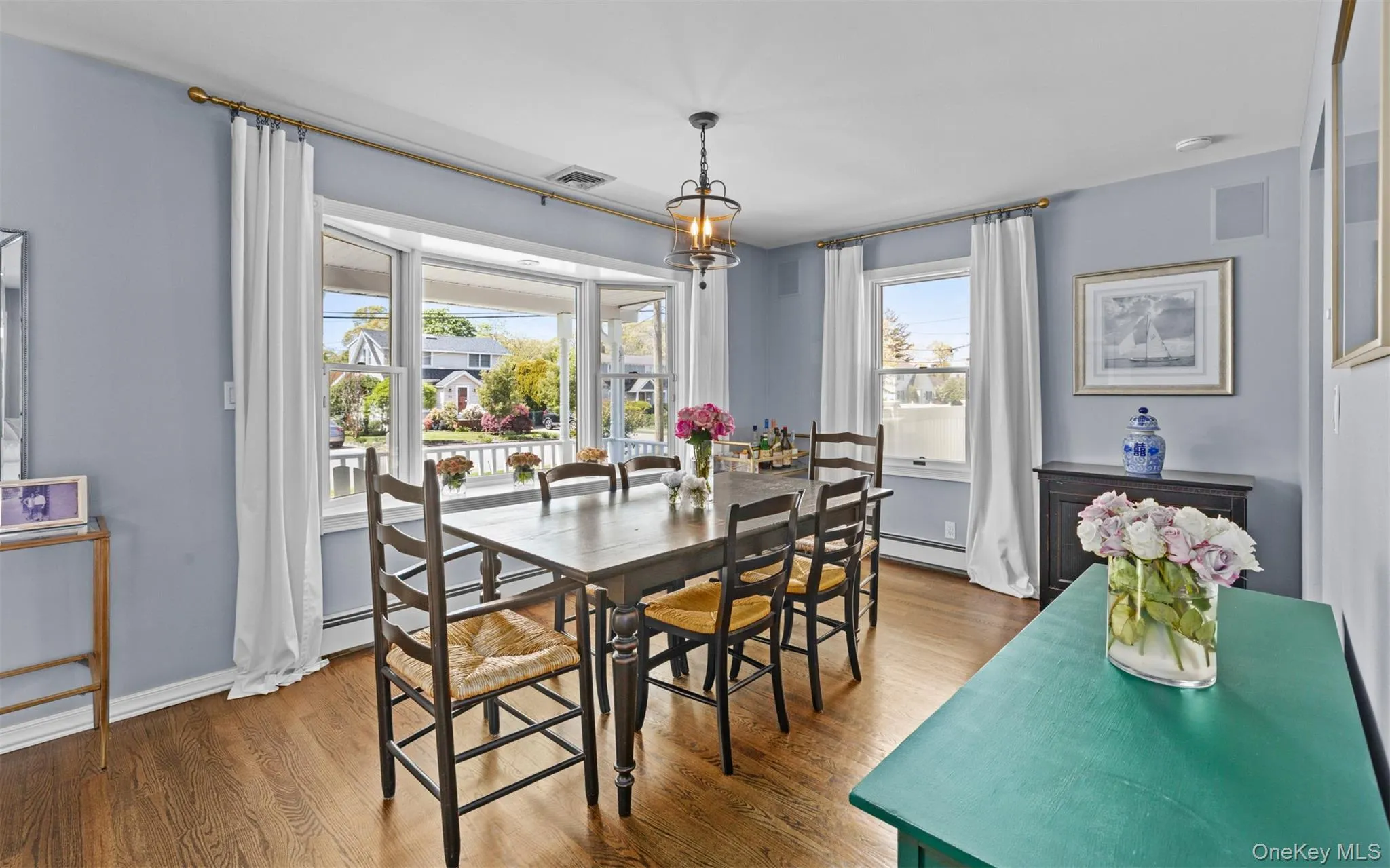 Dining room featuring wood flooring, a bay window with white trim Dining room featuring wood flooring, a bay window with white trim