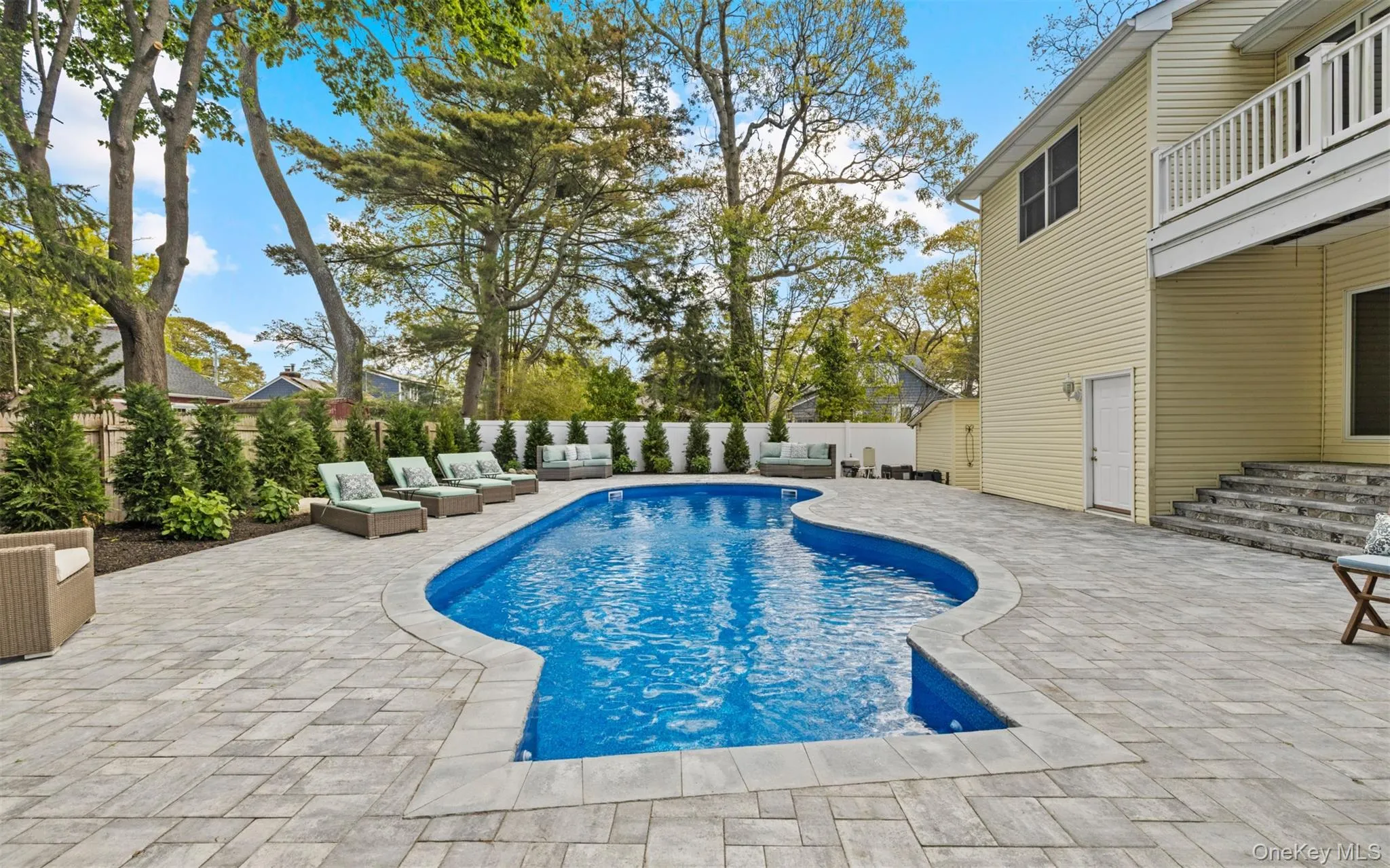 Free form in-ground pool with a surrounding paver patio and beautiful landscaping Free form in-ground pool with a surrounding paver patio and beautiful landscaping