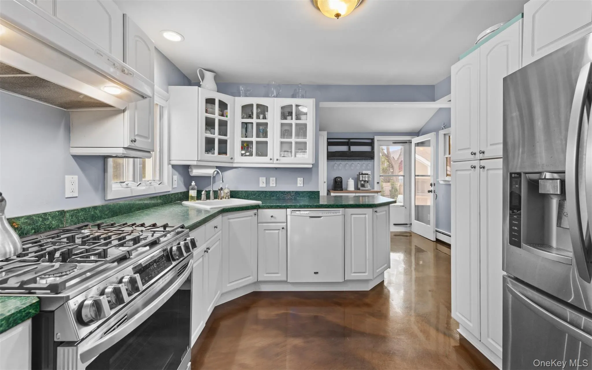 Kitchen featuring white cabinetry, formica countertops, stainless steel gas range, recessed lighting, and a stainless steel refrigerator Kitchen featuring white cabinetry, formica countertops, stainless steel gas range, recessed lighting, and a stainless steel refrigerator