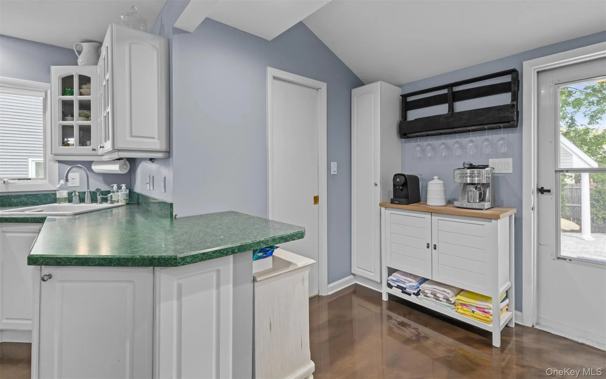 Kitchen featuring white cabinetry, a formica countertop, and wood flooring Kitchen featuring white cabinetry, a formica countertop, and wood flooring