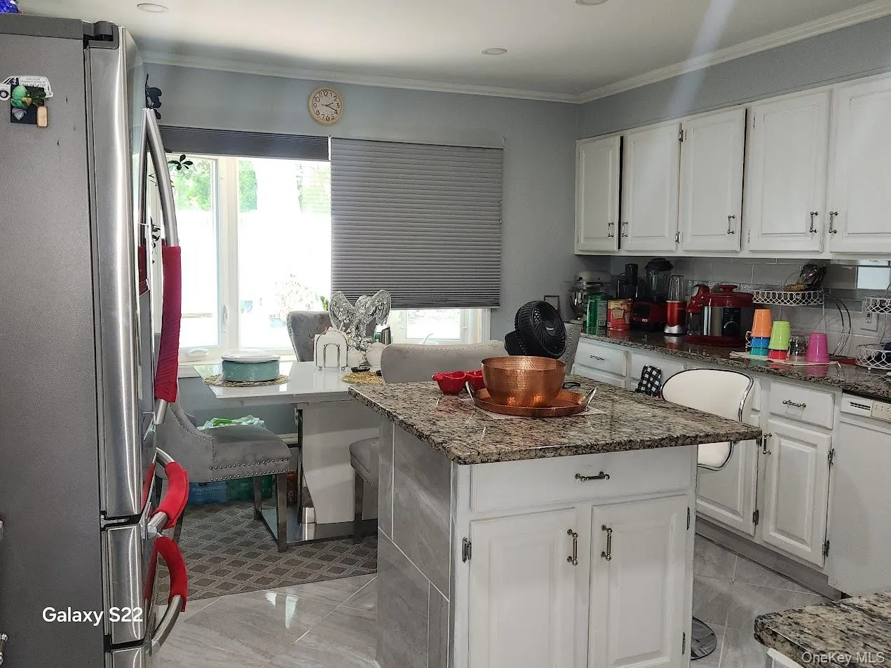 Kitchen featuring freestanding refrigerator, healthy amount of natural light, white cabinets, and ornamental molding Kitchen featuring freestanding refrigerator, healthy amount of natural light, white cabinets, and ornamental molding