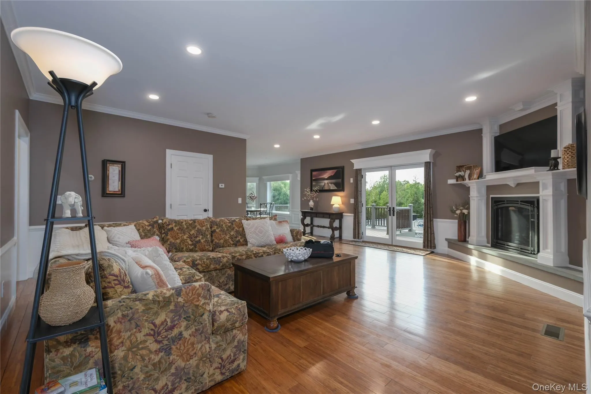 Living room with hardwood floors, recessed lighting, crown molding, a gas fireplace, and French doors to deck overlooking the in-ground pool complex. Living room with hardwood floors, recessed lighting, crown molding, a gas fireplace, and French doors to deck overlooking the in-ground pool complex.