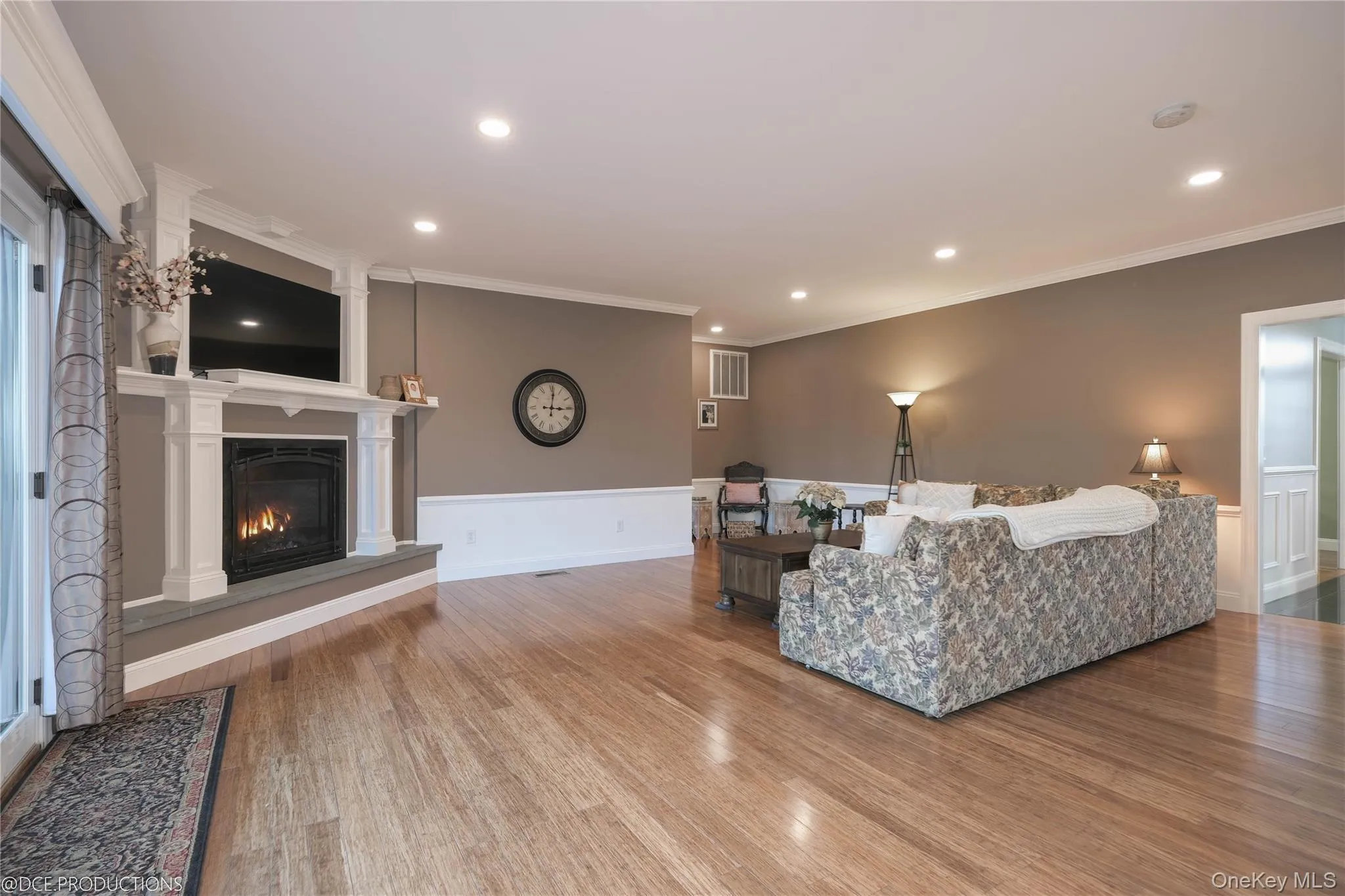 Living room featuring ornamental molding, a gas fireplace, wood finished floors, recessed lighting, and space to gather. Living room featuring ornamental molding, a gas fireplace, wood finished floors, recessed lighting, and space to gather.