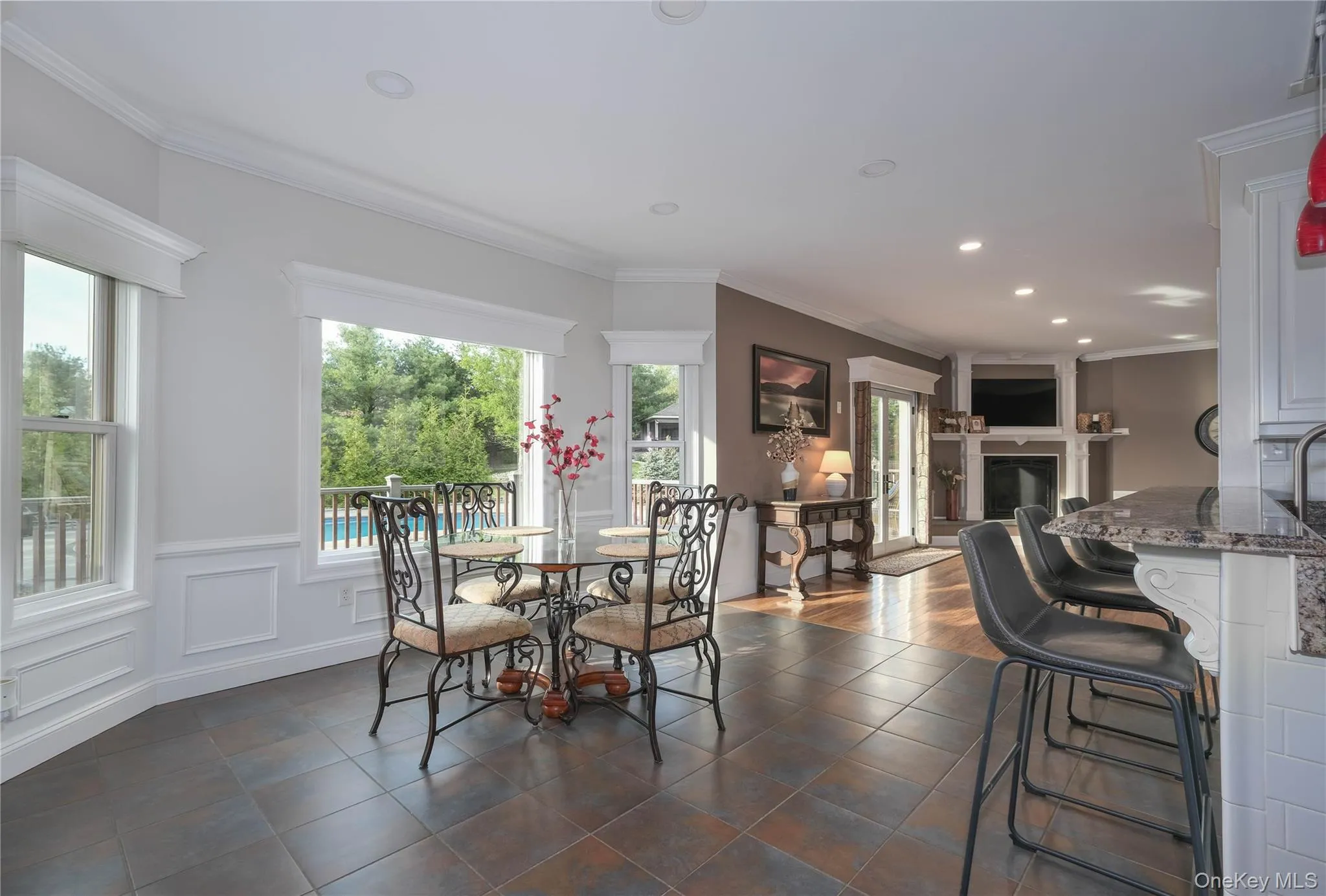 Dining area featuring tile flooring, crown molding, recessed lighting, wainscoting, breakfast bar and a view of the deck and pool complex. Dining area featuring tile flooring, crown molding, recessed lighting, wainscoting, breakfast bar and a view of the deck and pool complex.