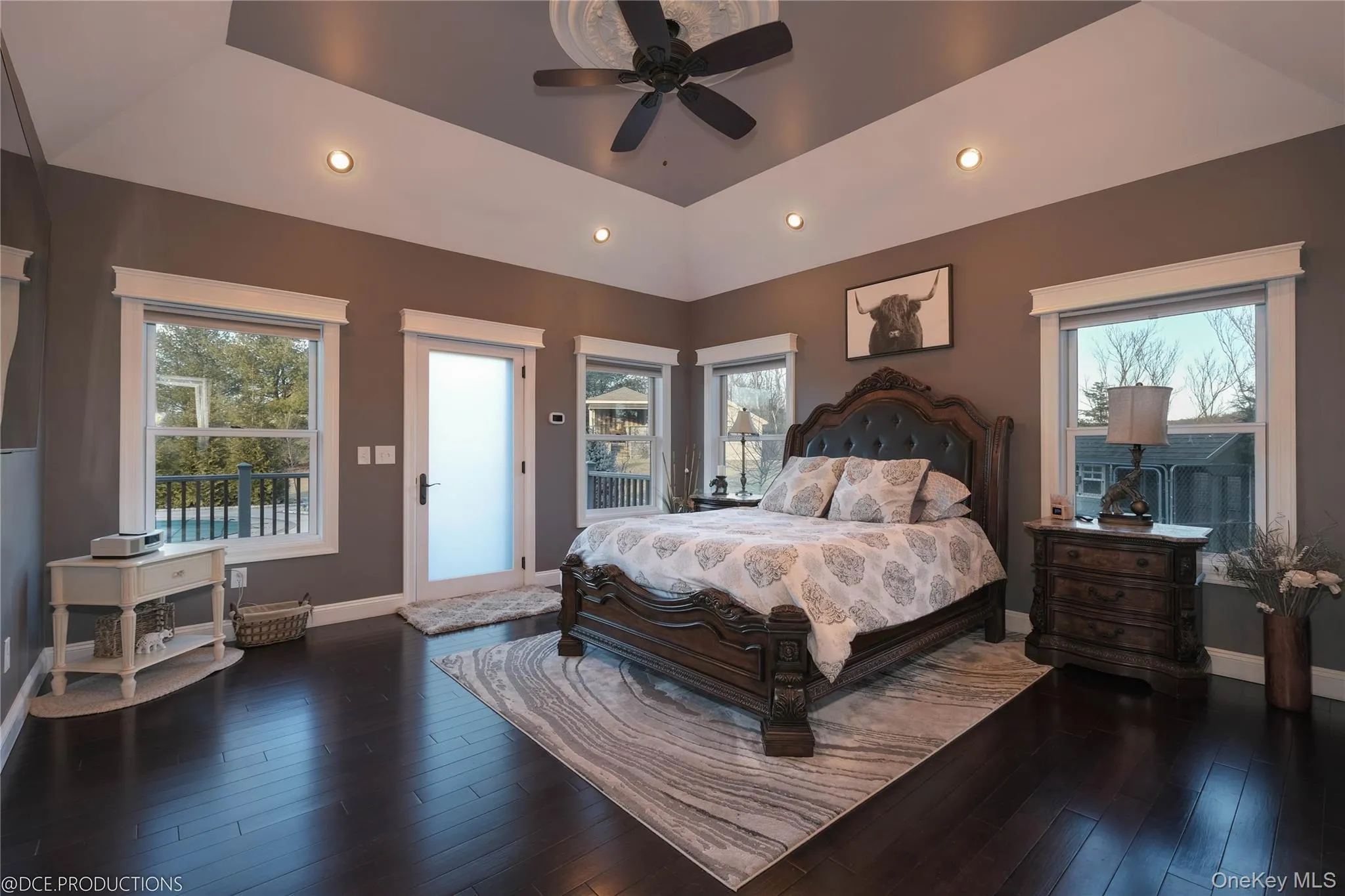 Main level Primary Bedroom suite with tray ceiling, hardwood floors, natural light, recessed lighting and direct access to rear deck. Main level Primary Bedroom suite with tray ceiling, hardwood floors, natural light, recessed lighting and direct access to rear deck.