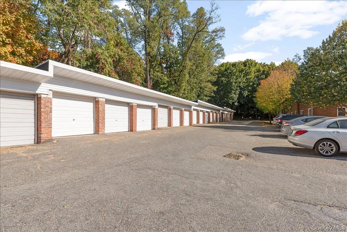 Row of attached garage units featuring white panel doors and brick pilasters Row of attached garage units featuring white panel doors and brick pilasters