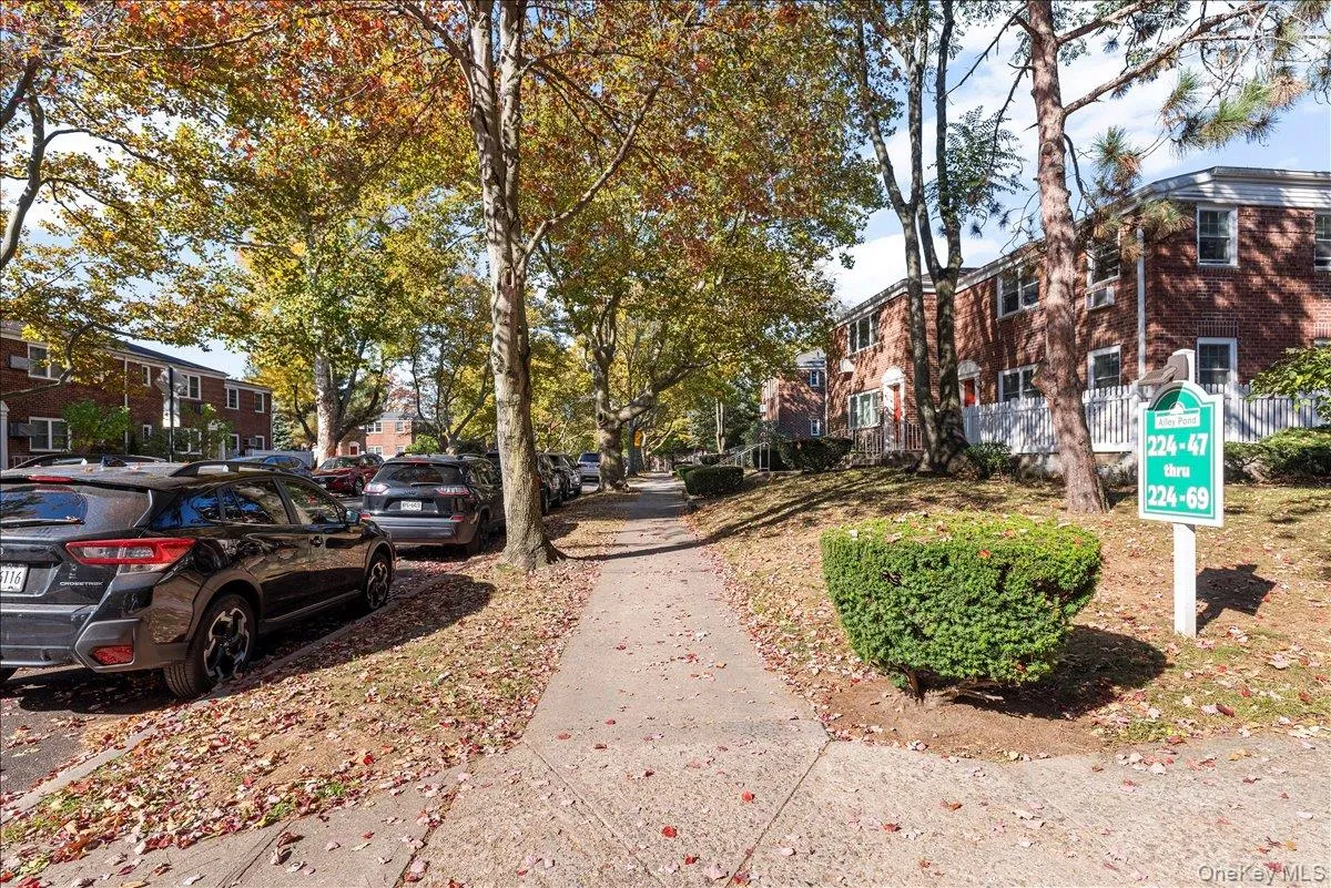 Brick facade residential buildings with white trim windows and mature trees along a concrete sidewalk Brick facade residential buildings with white trim windows and mature trees along a concrete sidewalk