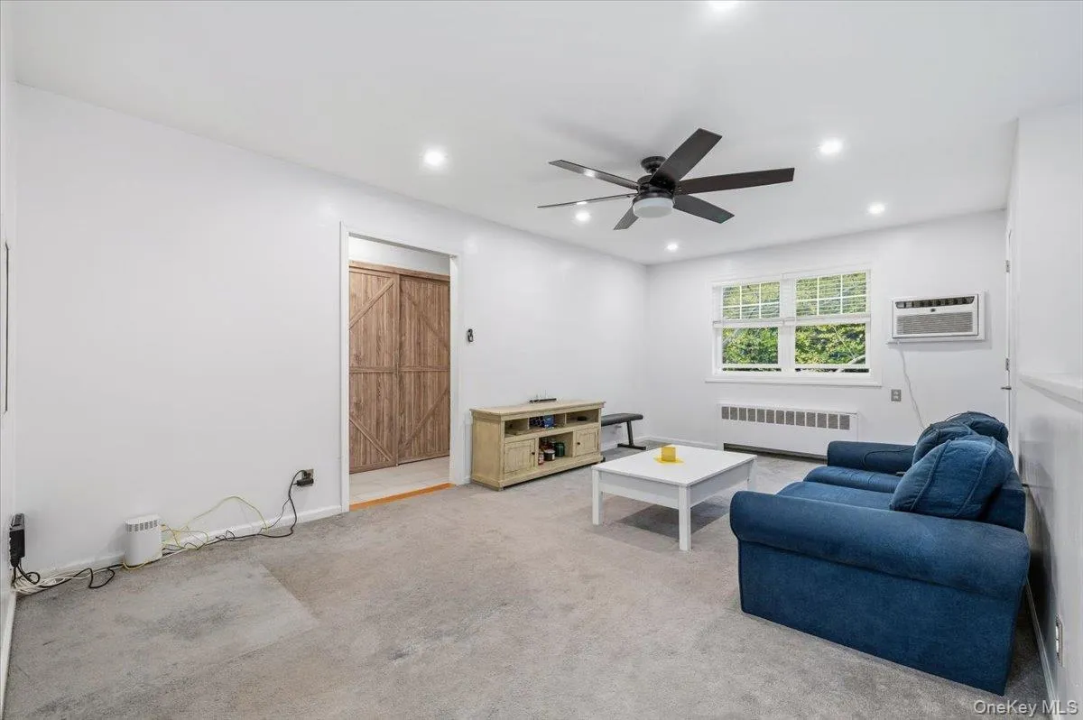 Carpeted living space featuring recessed lighting, a ceiling fan, a window air conditioning unit, and a window with exterior views Carpeted living space featuring recessed lighting, a ceiling fan, a window air conditioning unit, and a window with exterior views