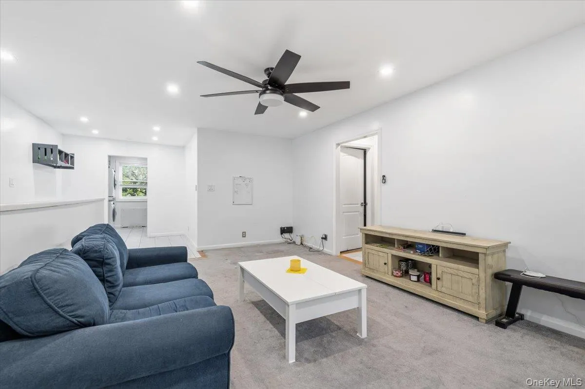 Spacious living area featuring light gray carpeting, recessed lighting, and a dark-toned ceiling fan Spacious living area featuring light gray carpeting, recessed lighting, and a dark-toned ceiling fan